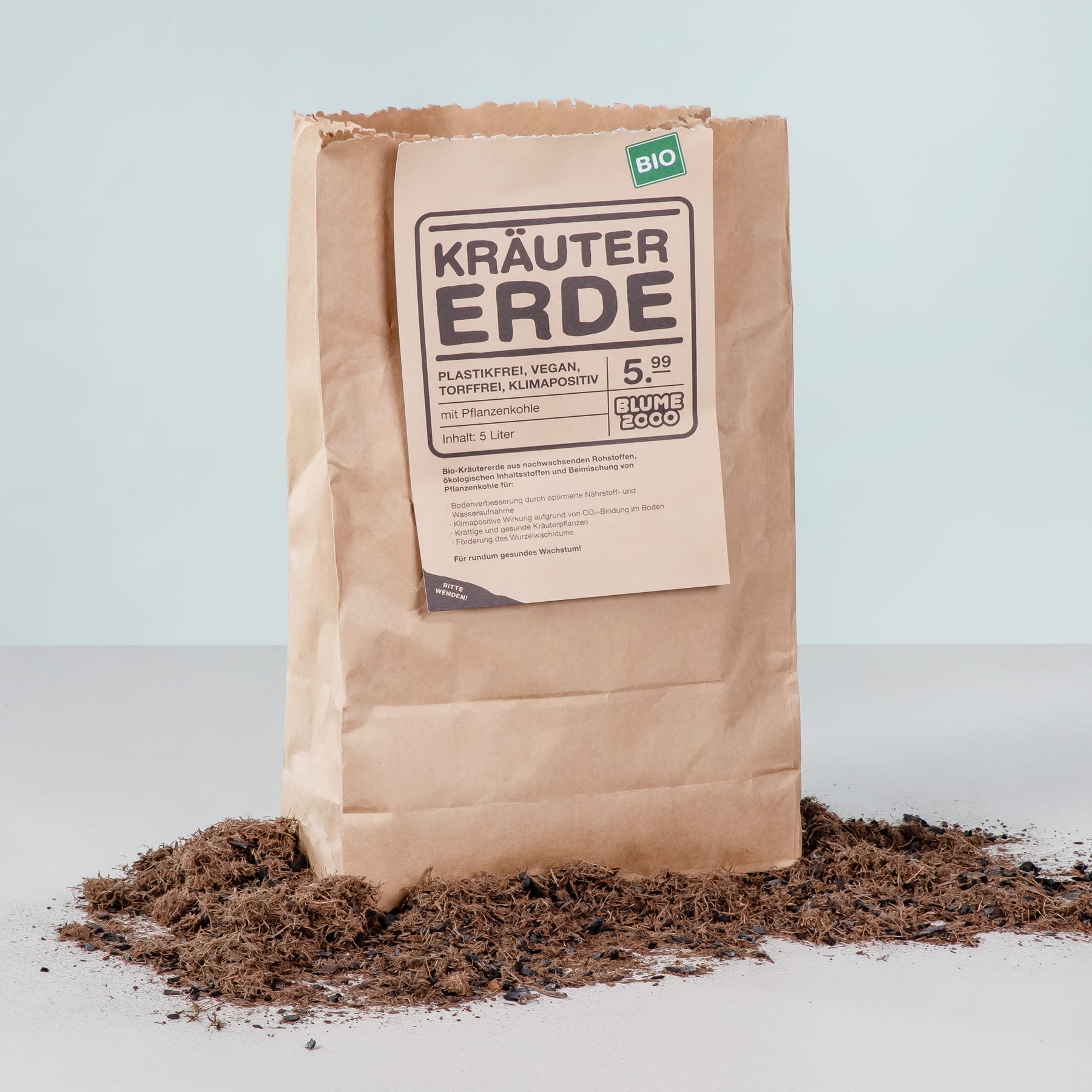 Auf einem Tisch steht eine Papiertüte mit der Aufschrift „Krauter Erde“, davor ist ein Teil des Inhalts verstreut.