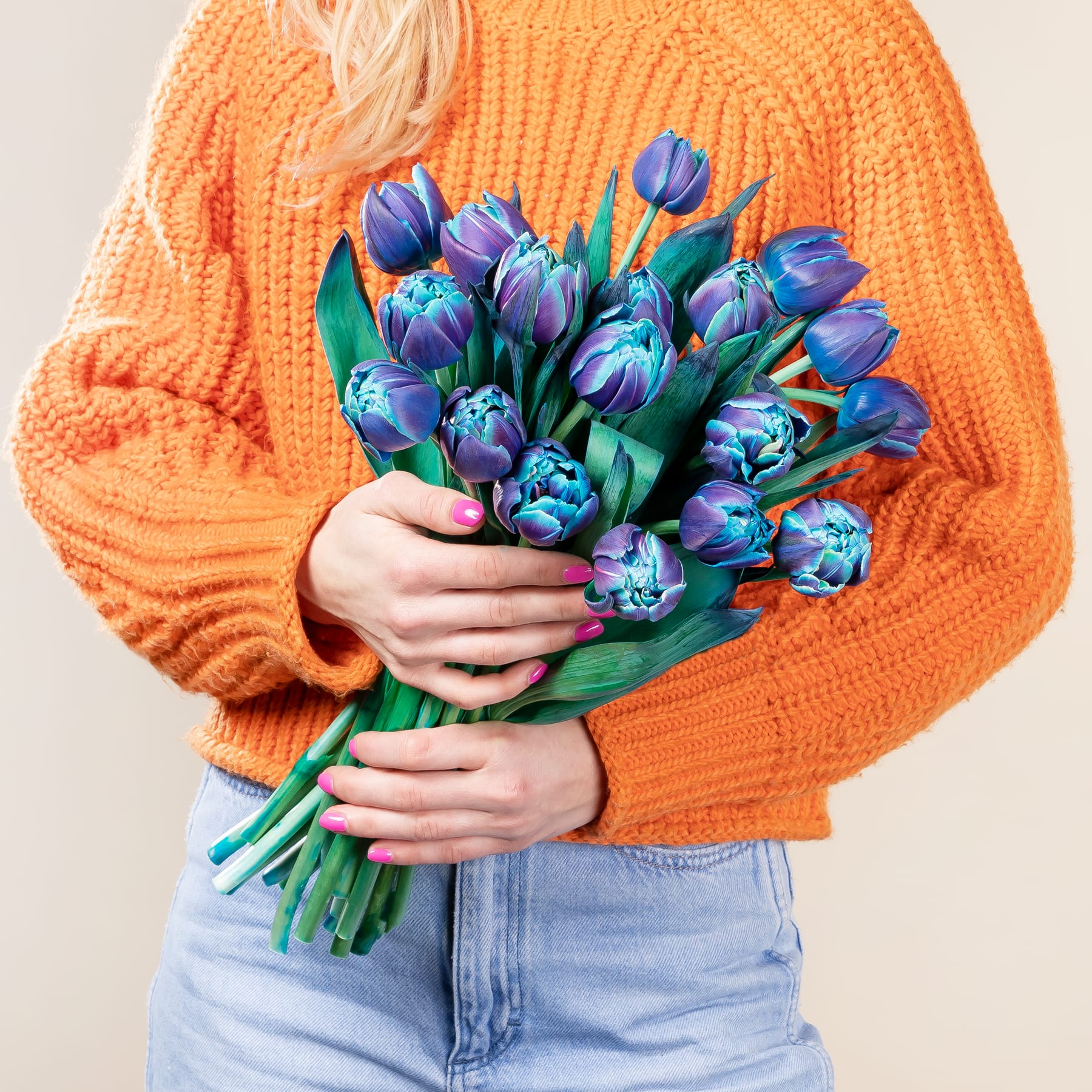 Ein lebendiger Strauß üppiger, violett-blauer, artischockenartiger Blüten vor einem weichen, neutralen Hintergrund.