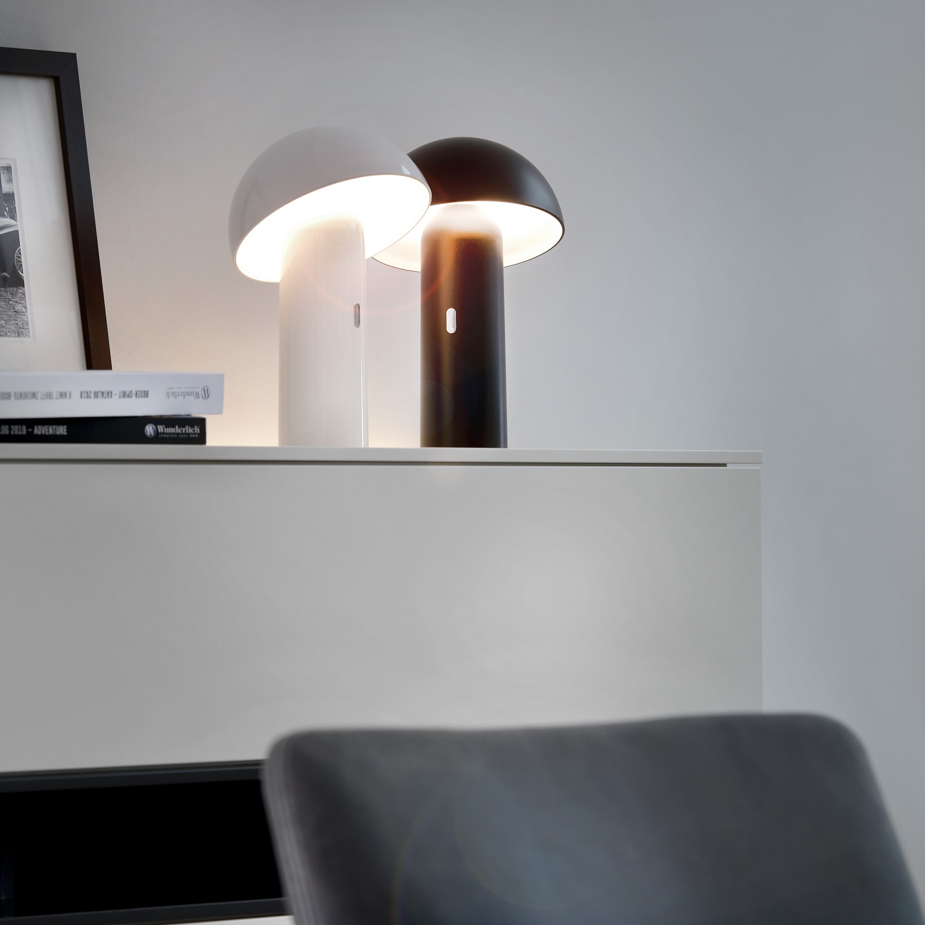 Das Bild zeigt eine moderne, minimalistische Schreibtischeinrichtung mit einem eleganten, weißen Schreibtisch und einem Paar einzigartiger, kuppelförmiger Lampen, die für Beleuchtung sorgen.