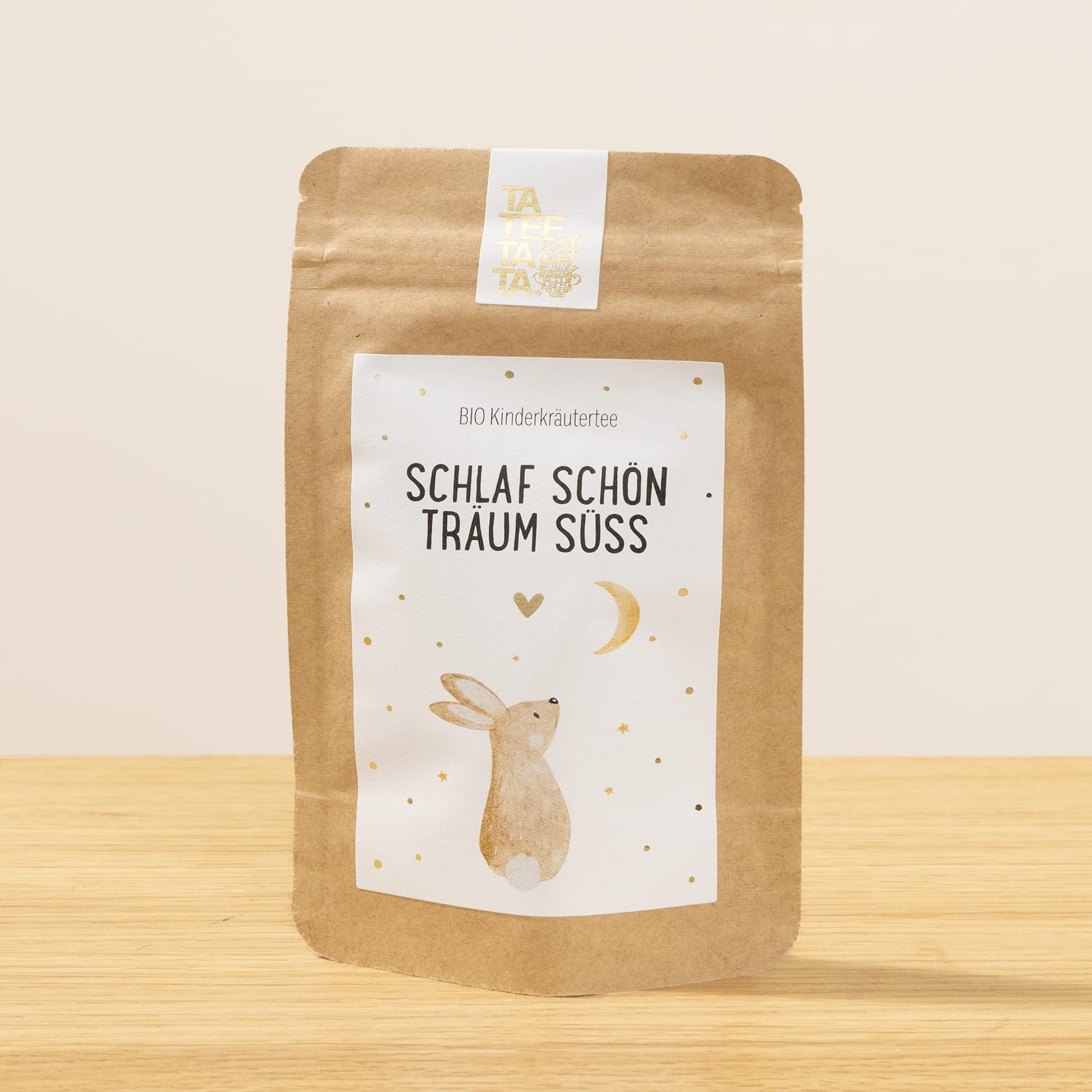 Eine braune Papiertüte mit weißem Etikett, auf dem sich auf einer Holzoberfläche die Illustration eines schlafenden Kaninchens und der Text „Schlaf schon traum suss“ befinden.