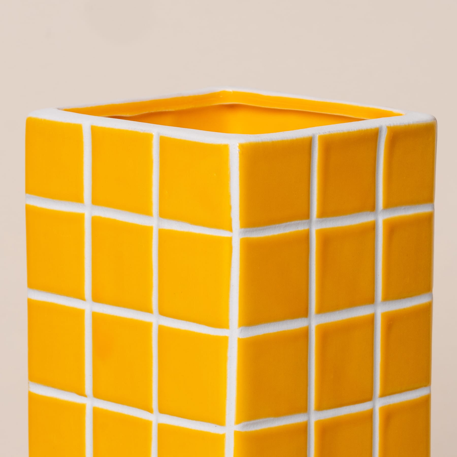 Ein leuchtend gelbes, würfelförmiges Objekt mit einem gitterartigen Muster auf der Oberfläche, vor einem schlichten, hellen Hintergrund.