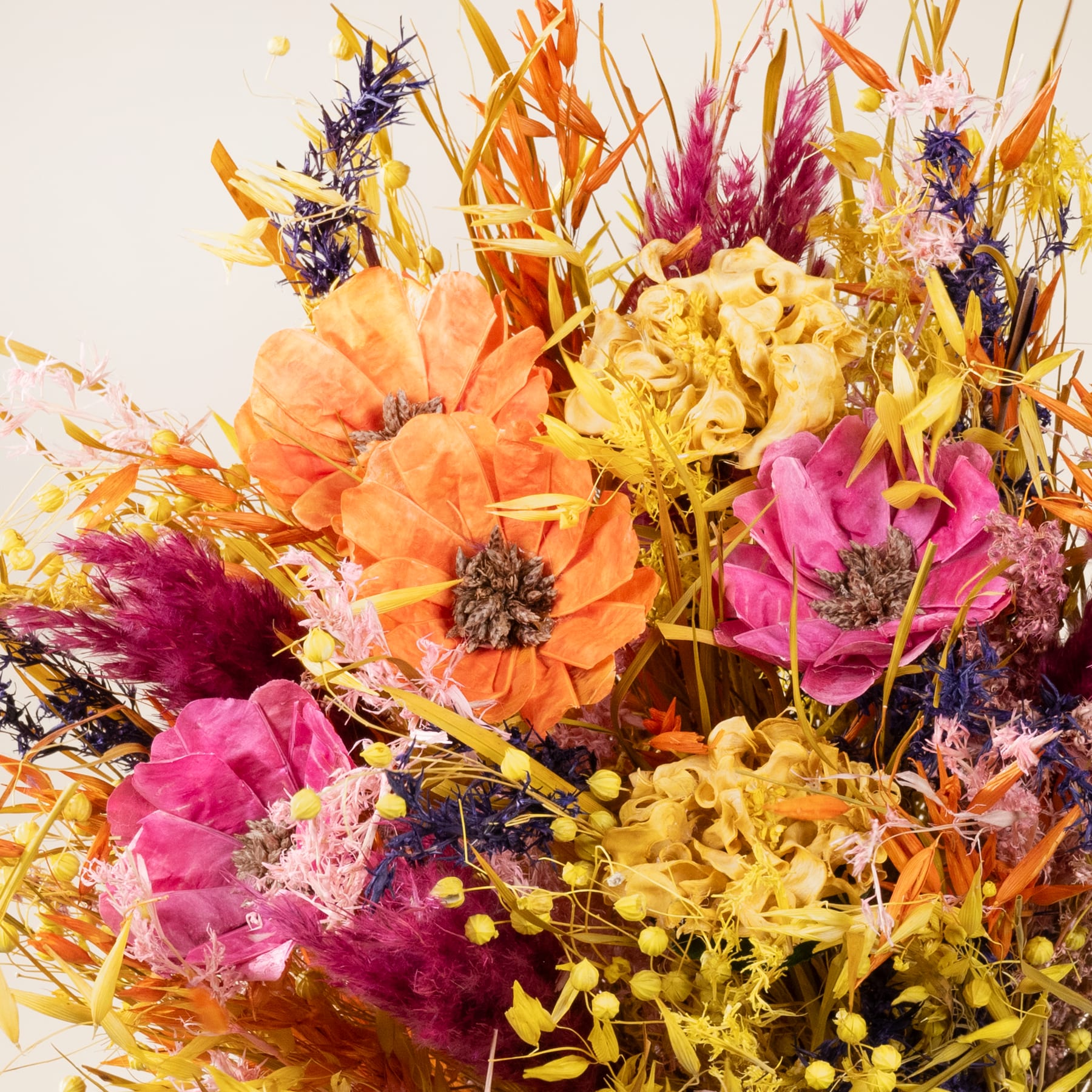 Ein lebendiger Strauß bunter Blumen, darunter große orangefarbene Dahlien, rosa Rosen und gelbe Chrysanthemen, vor einem schlichten Hintergrund.