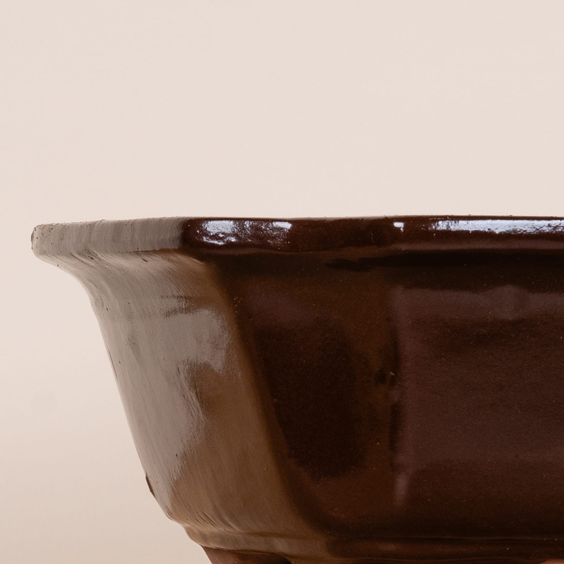 Eine dunkle, glänzende Keramikschüssel steht auf einer schlichten, hellen Oberfläche.