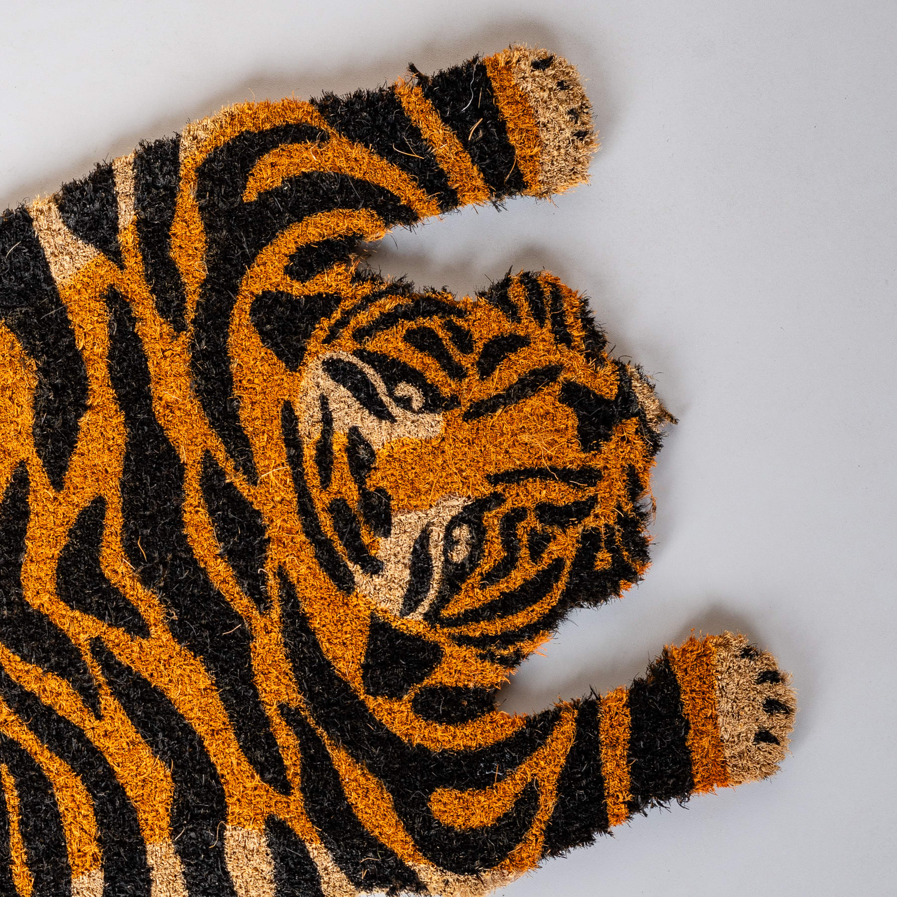 Eine Nahaufnahme des Gesichts eines Tigers mit seinem charakteristischen orange-schwarz gestreiften Fellmuster und seinem intensiven Blick vor einem schlichten Hintergrund.