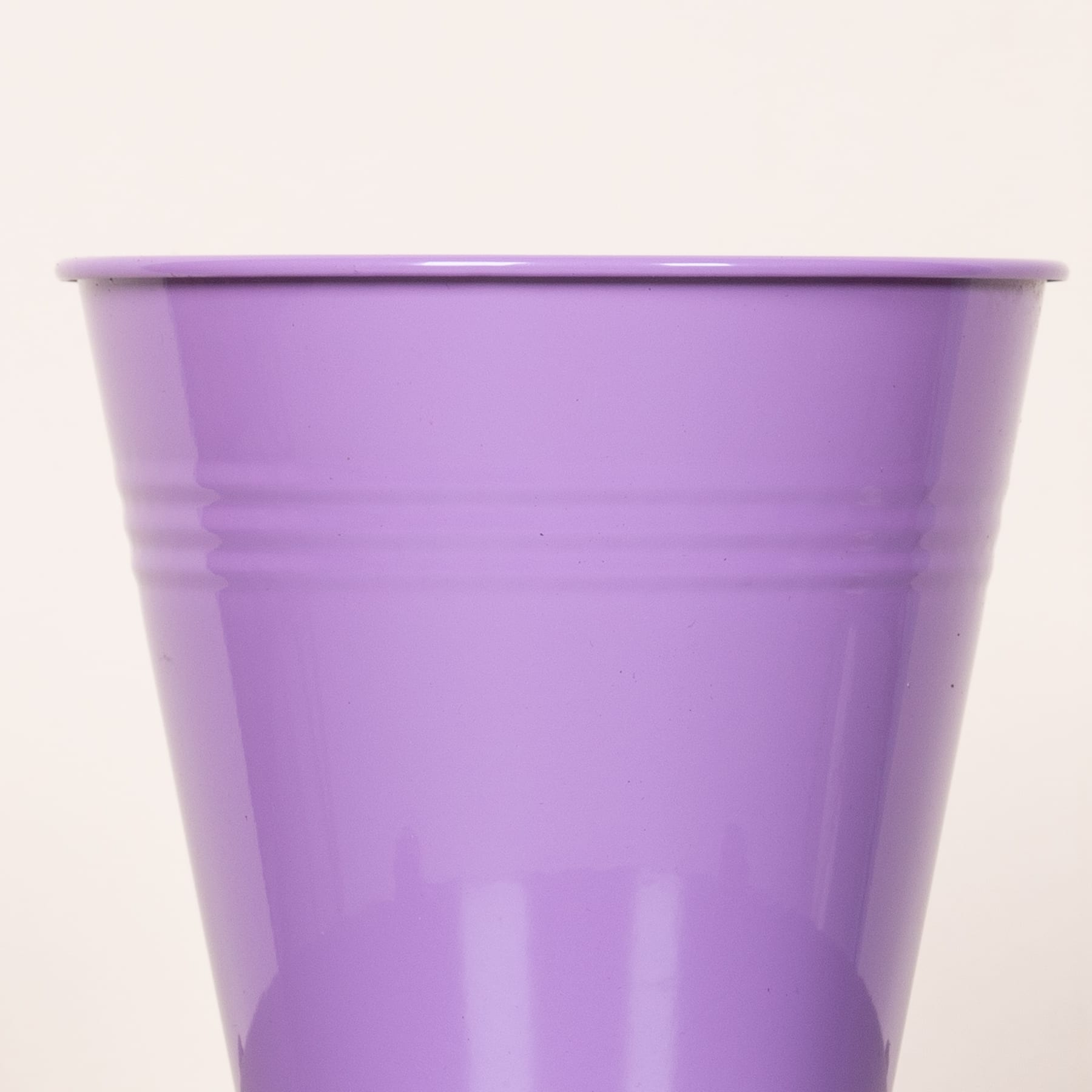 Ein leuchtend violetter Plastikbecher oder -behälter mit glatter, gleichmäßiger Oberfläche und leicht gewölbtem Rand vor einem schlichten, hellen Hintergrund.