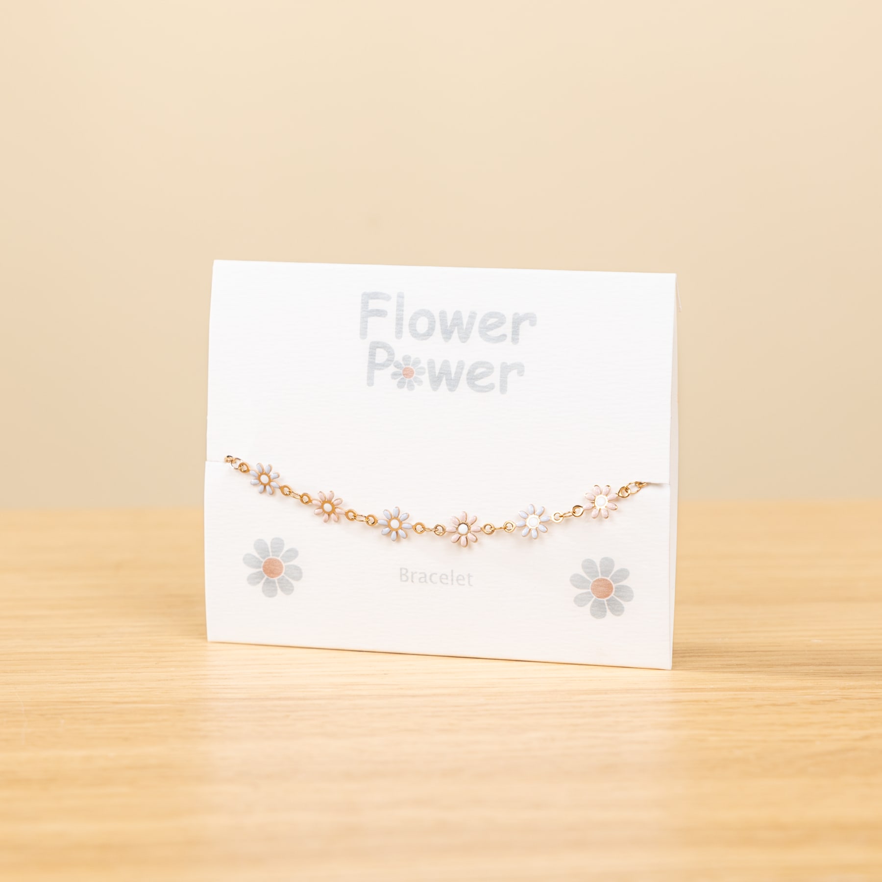 Eine weiße Karte mit dem Text „Flower Power“ zeigt eine zarte Blumenkette auf einer Holzoberfläche vor einem hellbeigen Hintergrund.