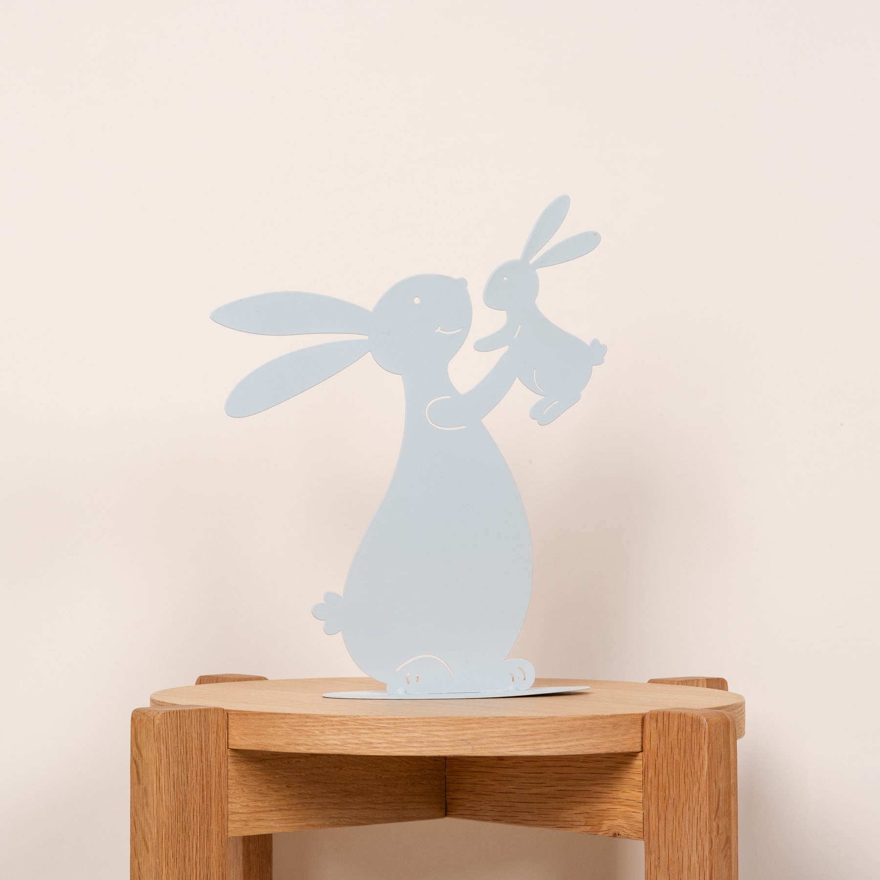 Ein Holzständer mit der Silhouette einer kaninchenähnlichen Figur, die einen Schatten auf die Wand dahinter wirft.