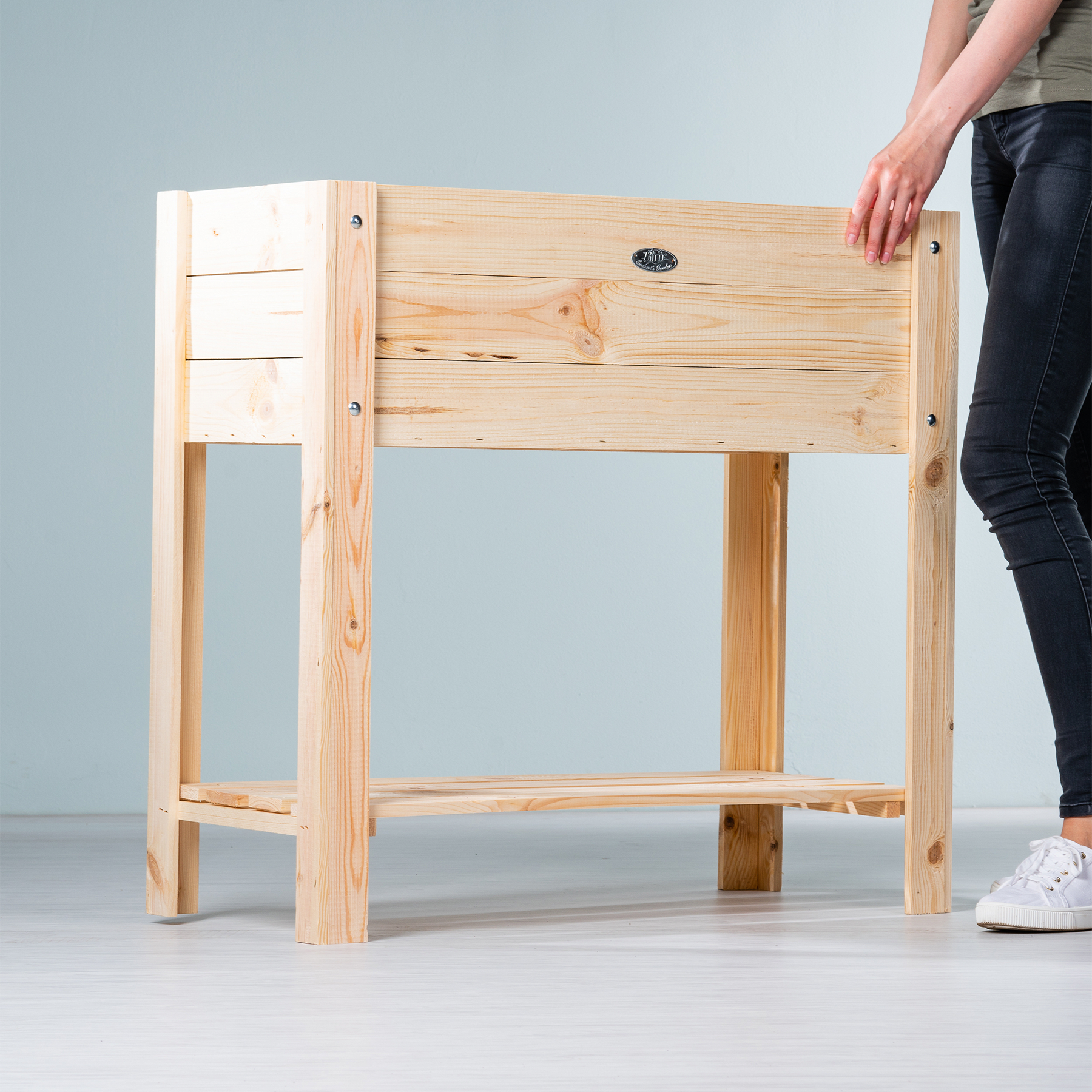 Eine hölzerne Werkbank oder ein Tisch mit Schubladen steht in minimalistischer Umgebung vor einem schlichten grauen Hintergrund.