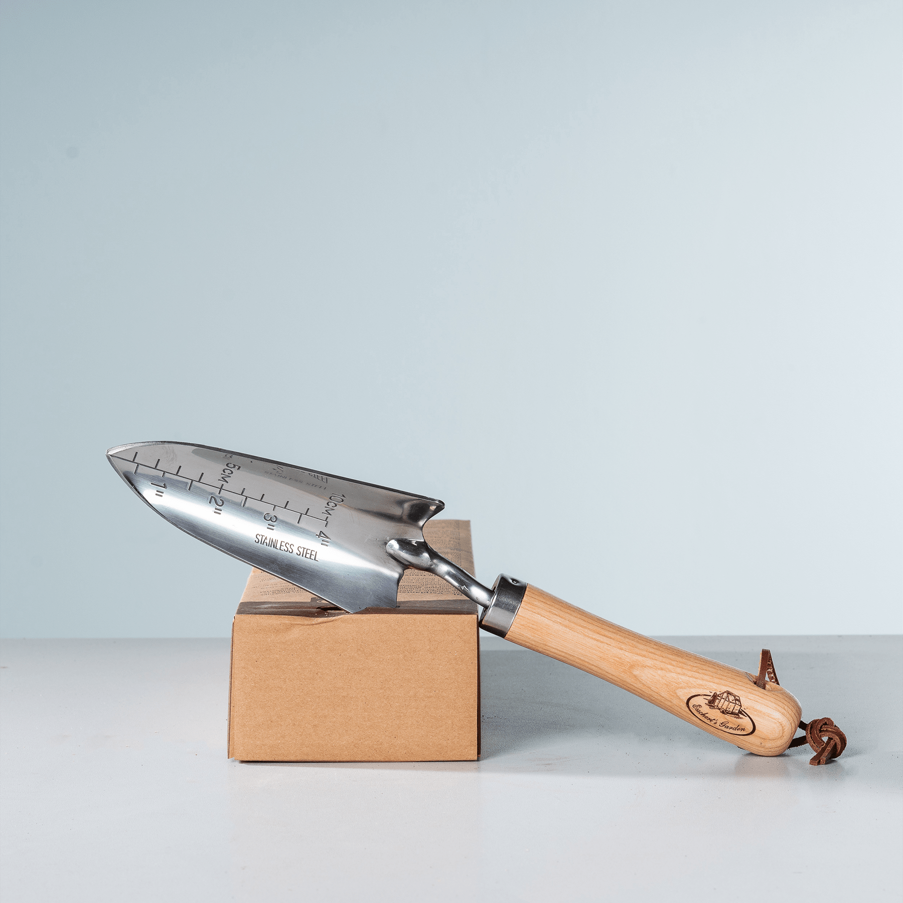 Ein silberfarbenes Universalmesser liegt auf einem Karton vor einem schlichten, hellen Hintergrund.