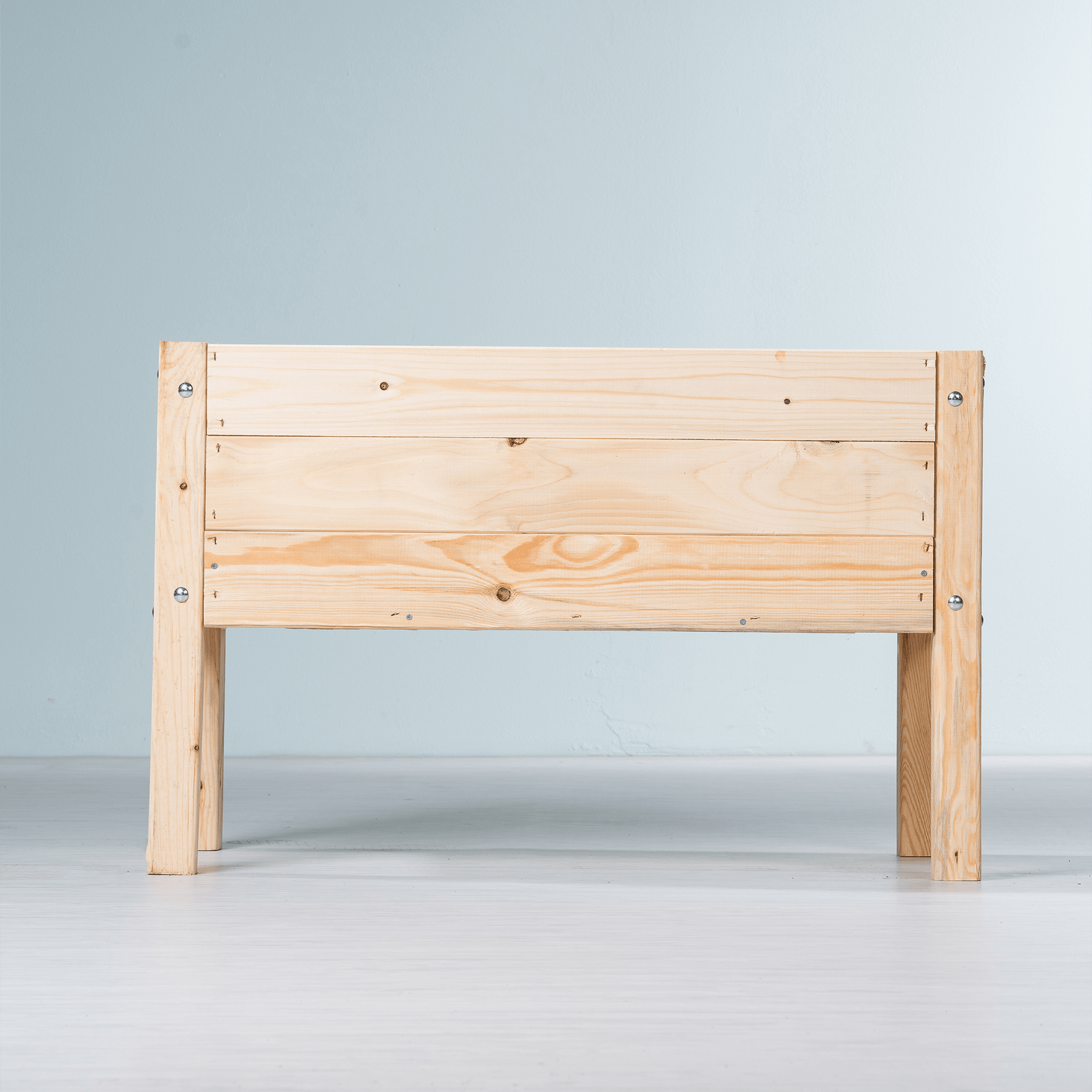 Eine einfache Holzbank oder ein Kopfteil vor einem schlichten, hellen Hintergrund.