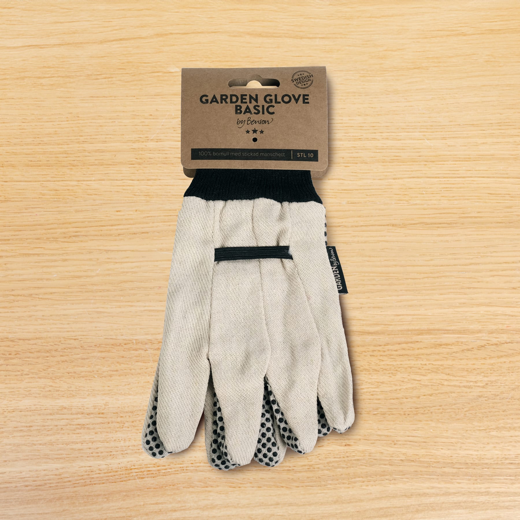 Auf einer Holzoberfläche liegt ein Paar weiß-schwarze Gartenhandschuhe mit der Aufschrift „Garden Glove Basic“.