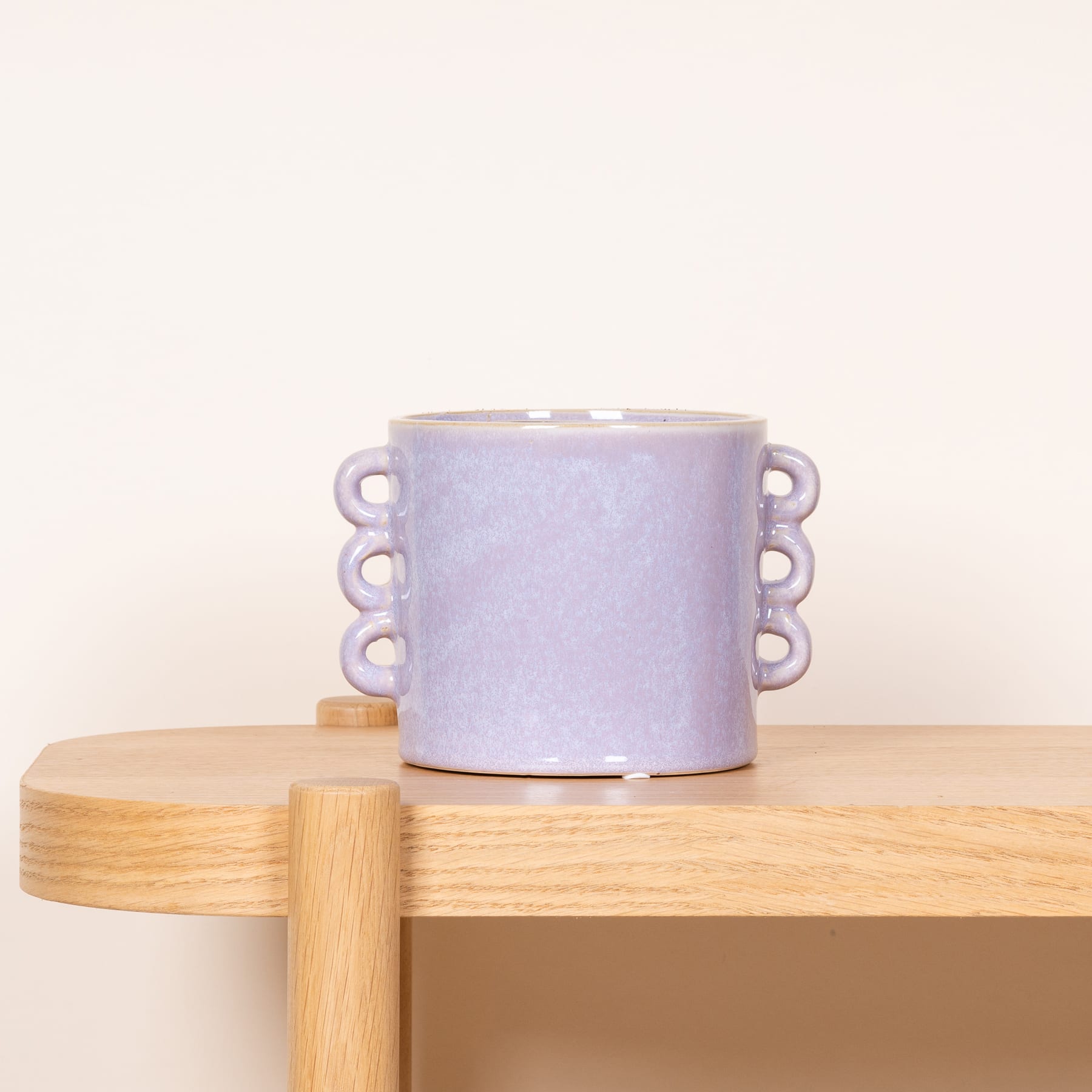 Auf einer Holzoberfläche steht eine lavendelfarbene Keramiktasse mit schlichtem, minimalistischem Design.