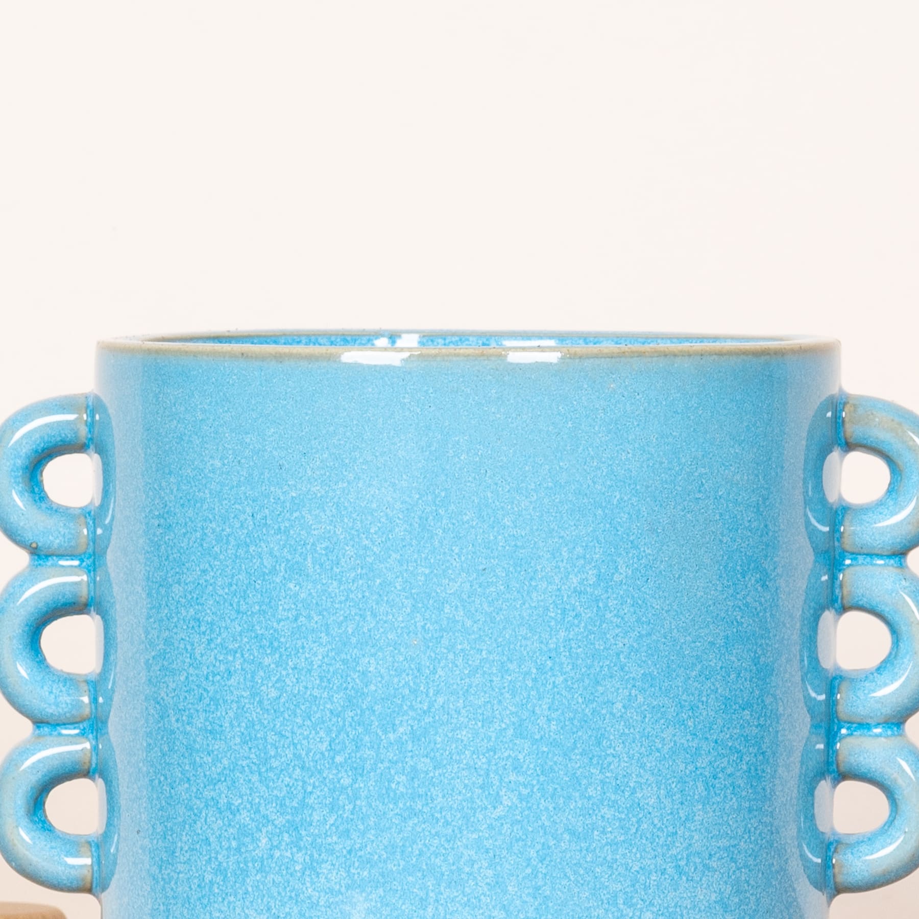 Eine hellblaue Keramiktasse mit strukturierter Oberfläche und mehreren Henkeln.