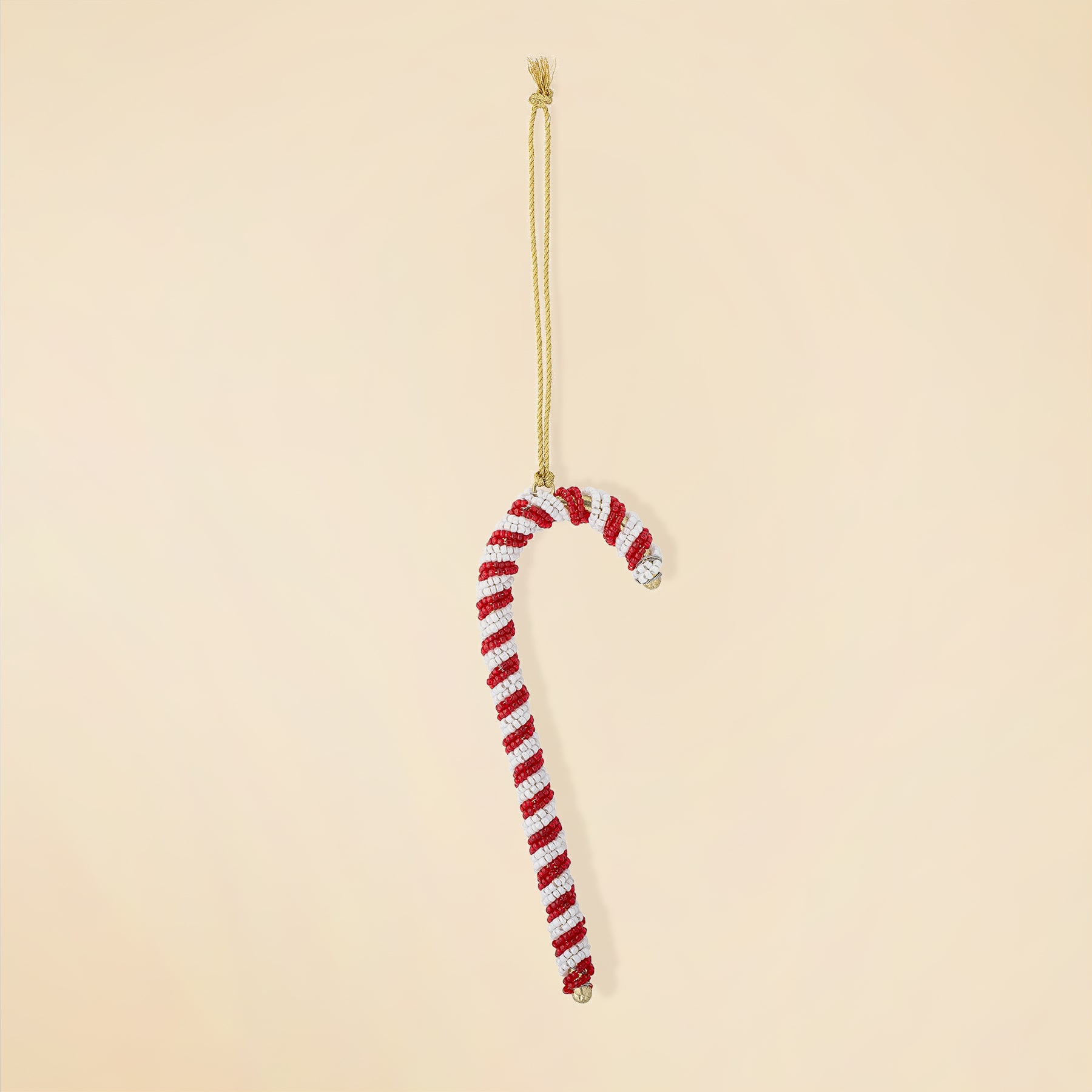 Ein rot-weiß gestreiftes Zuckerstangen-Ornament hängt vor einem schlichten, cremefarbenen Hintergrund.