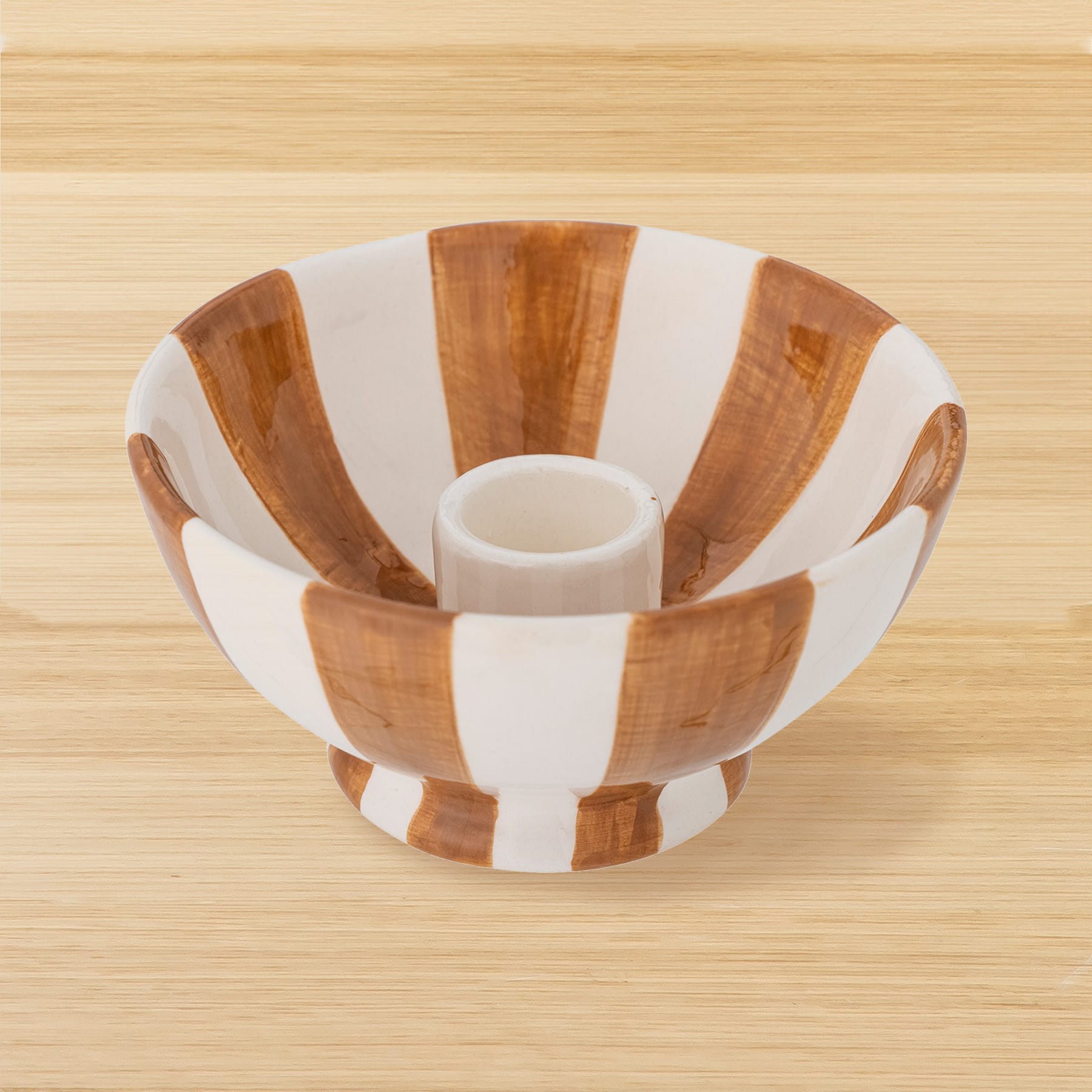 Eine weiß-braun gestreifte Keramikschüssel steht auf einer Holzoberfläche.