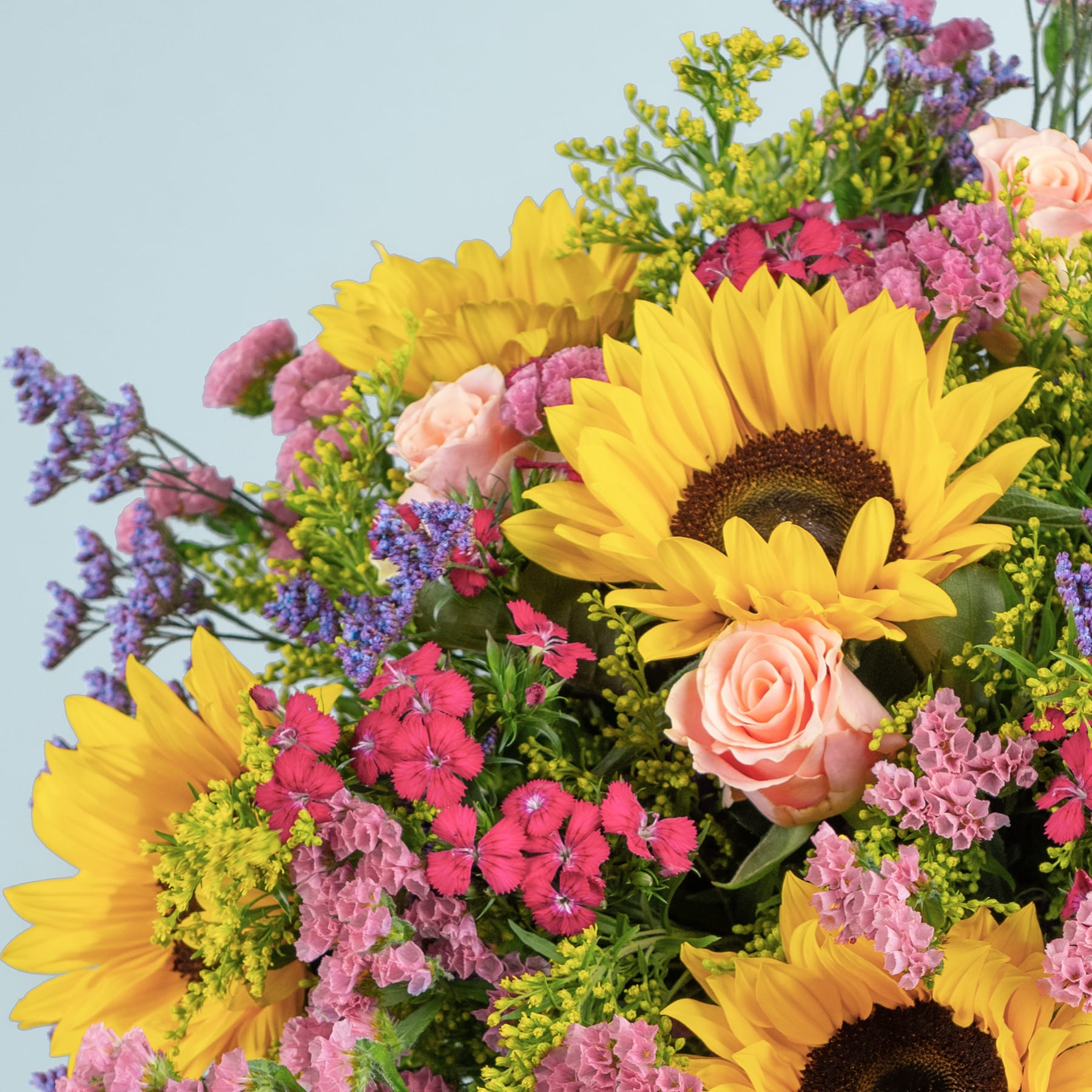 Ein lebendiger Strauß aus Sonnenblumen, Rosen und anderen bunten Blumen vor einem sanften blauen Hintergrund.