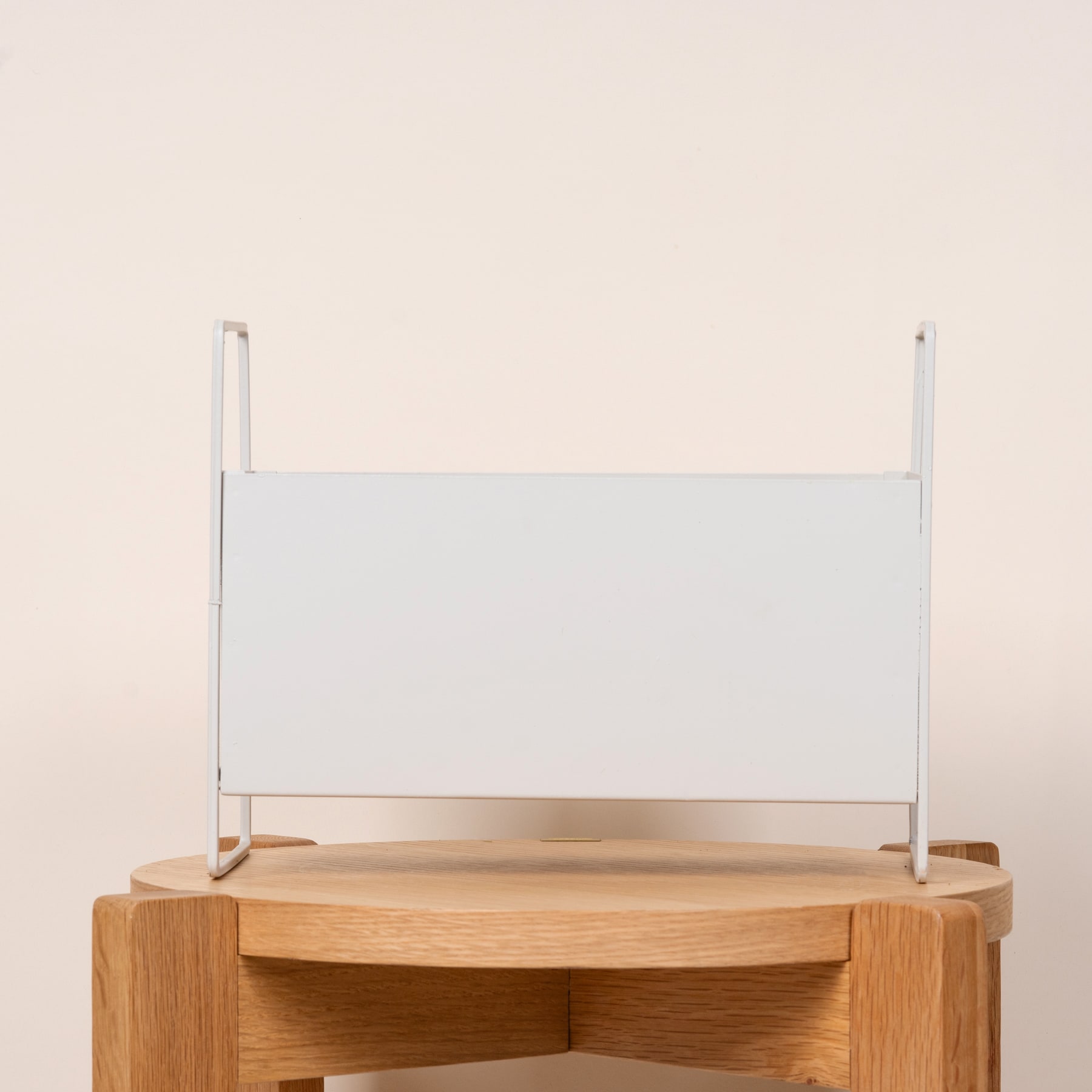 Ein einfaches, minimalistisches Design mit einem weißen rechteckigen Panel, das auf einer Holzplattform montiert ist.