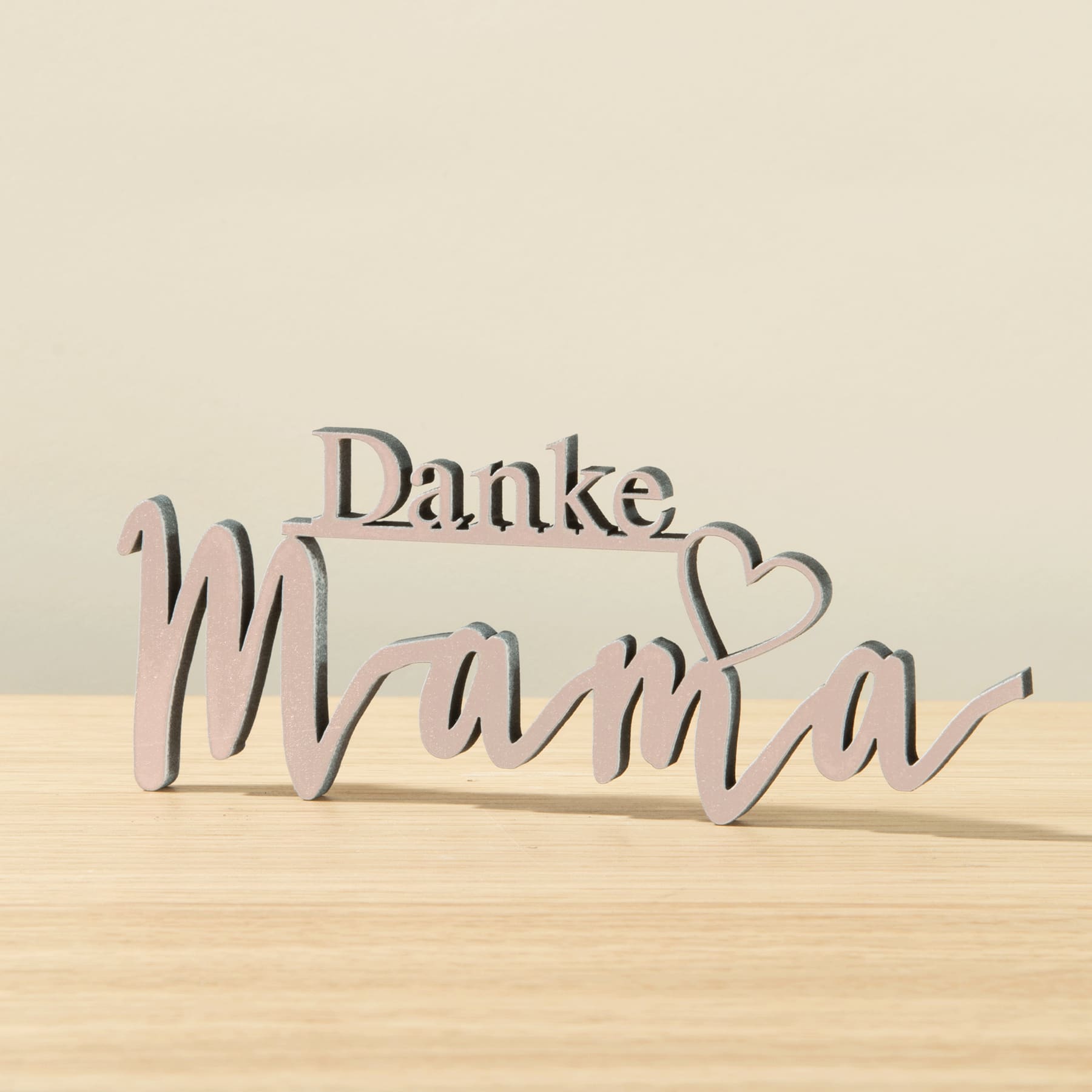Das Bild zeigt das deutsche Wort „Danke Mama“ aus Holzbuchstaben auf einer Holzoberfläche.