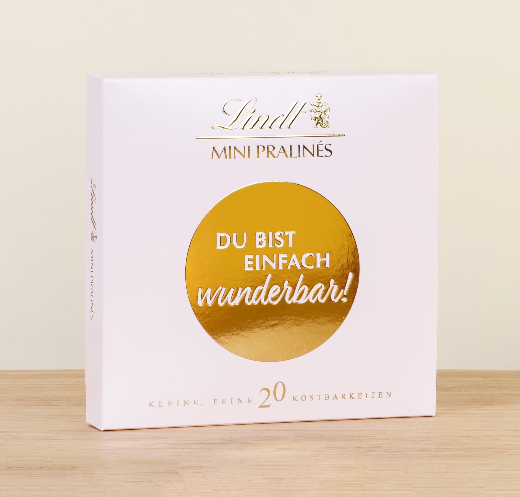 In einer weißen Schachtel mit einem goldenen, runden Etikett und der Aufschrift „Du bist einfach wunderbar!“ befindet sich eine Schachtel Lindt Mini-Pralinen.