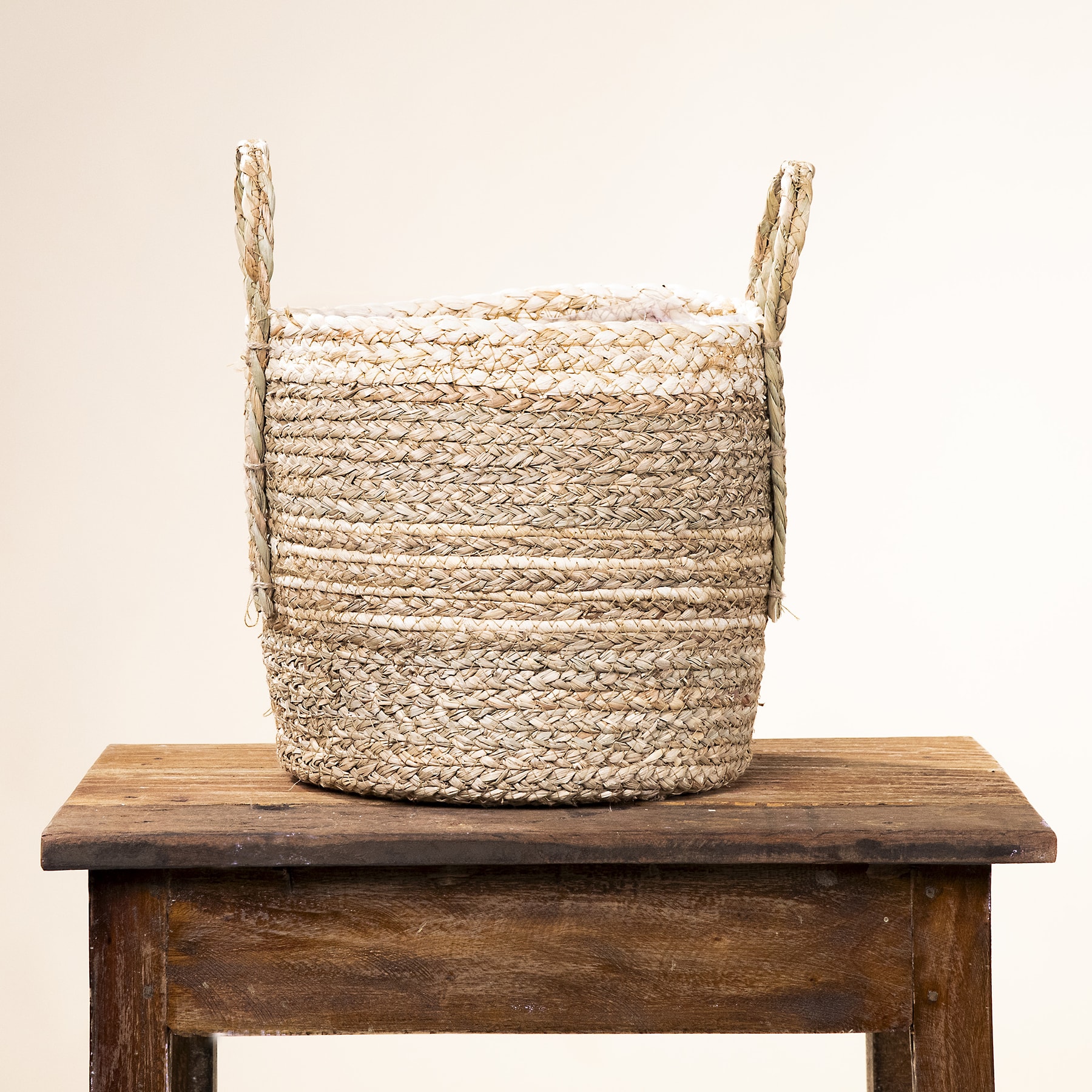 Auf einem rustikalen Holztisch steht vor einem schlichten Hintergrund ein geflochtener Korb.