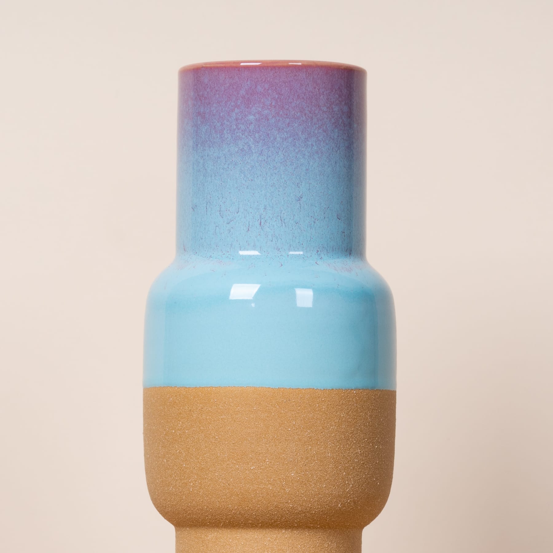 Eine farbenfrohe Keramikvase mit einem Farbverlauf aus Blau-, Rosa- und Goldtönen.