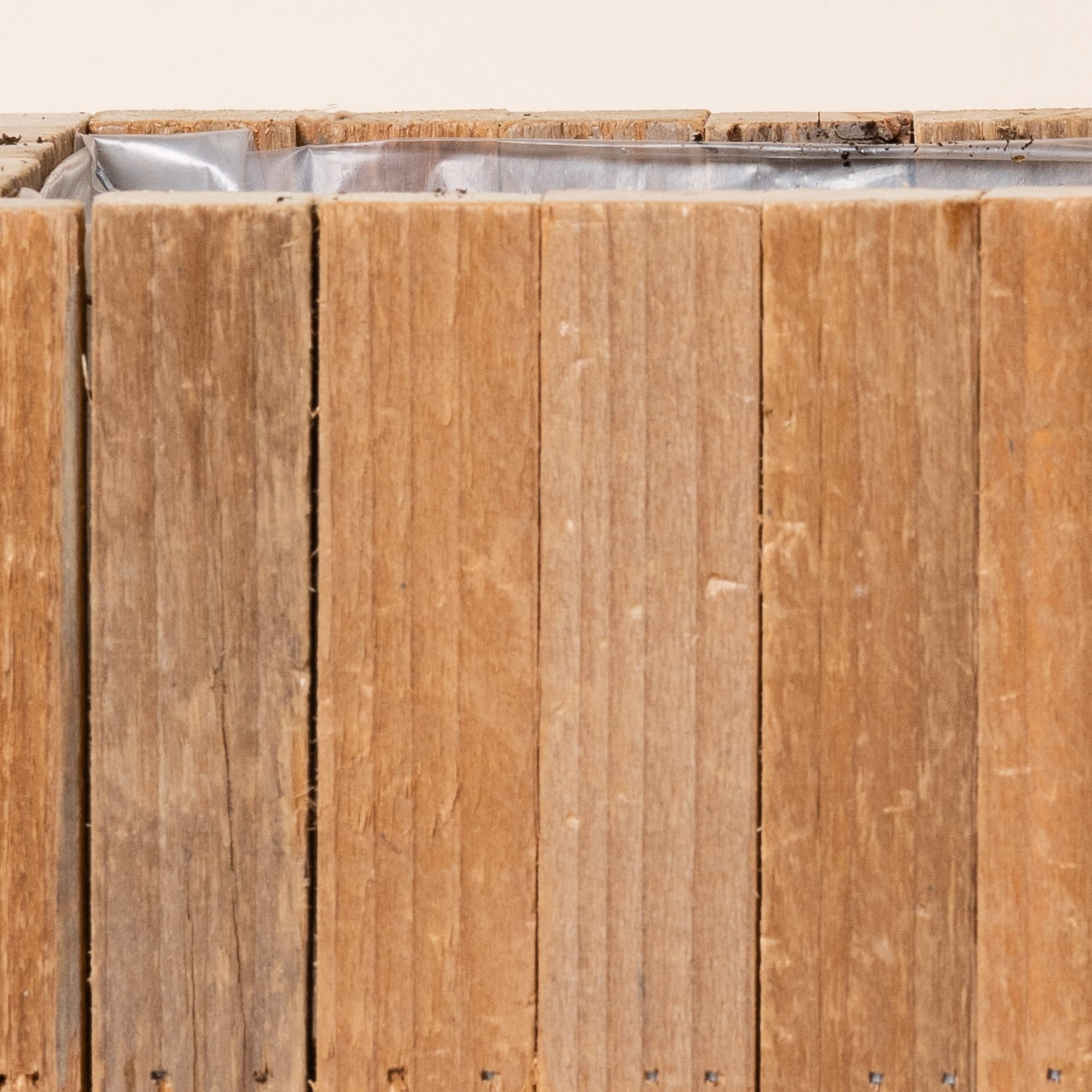 Ein Holzzaun oder eine Holzmauer aus vertikalen Holzbrettern, auf deren Oberfläche einige Verwitterungserscheinungen und Verfärbungen sichtbar sind.