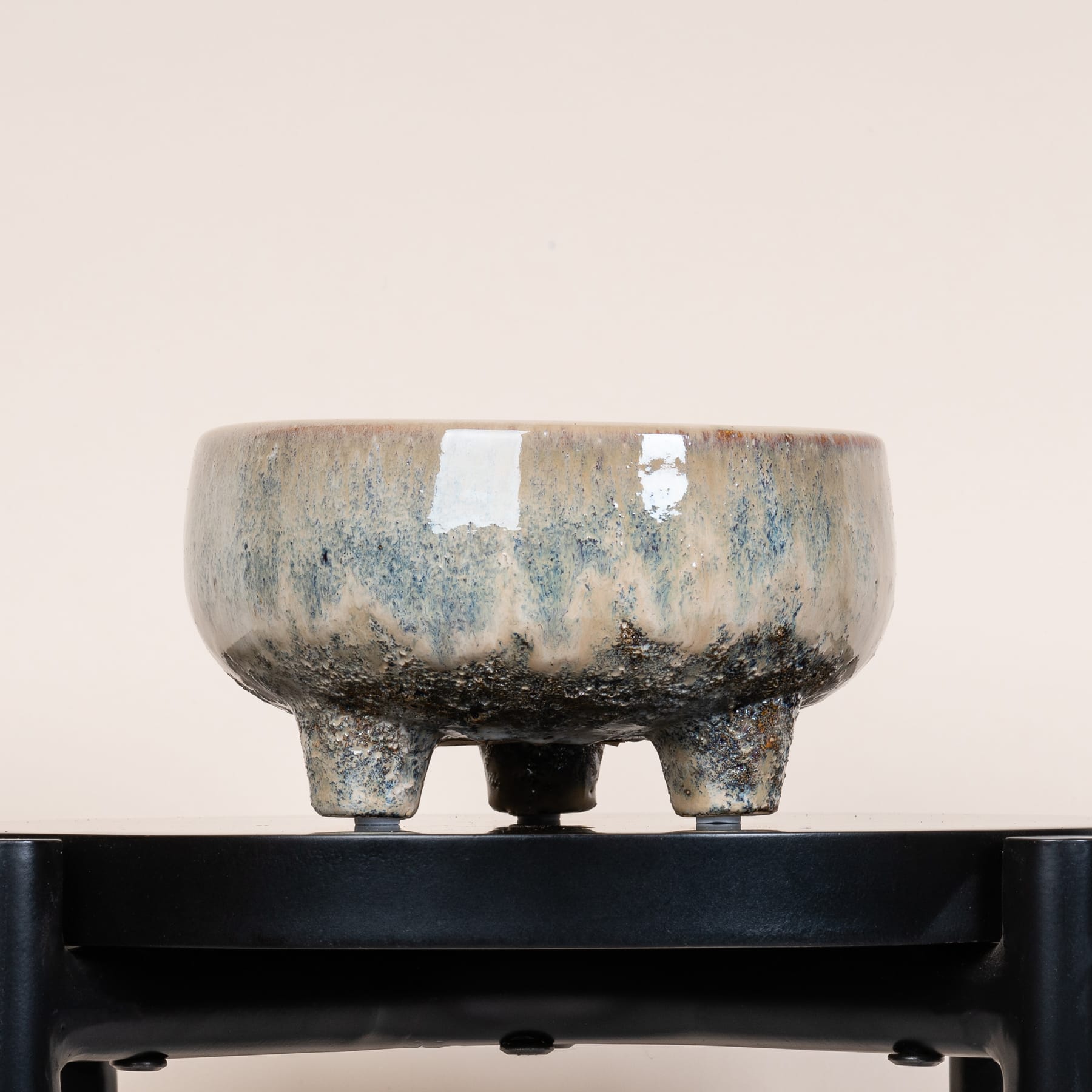 Eine Keramikschale mit gesprenkelter, erdiger Glasur steht auf einer schwarzen Oberfläche und schafft so eine minimalistische und optisch beeindruckende Komposition.