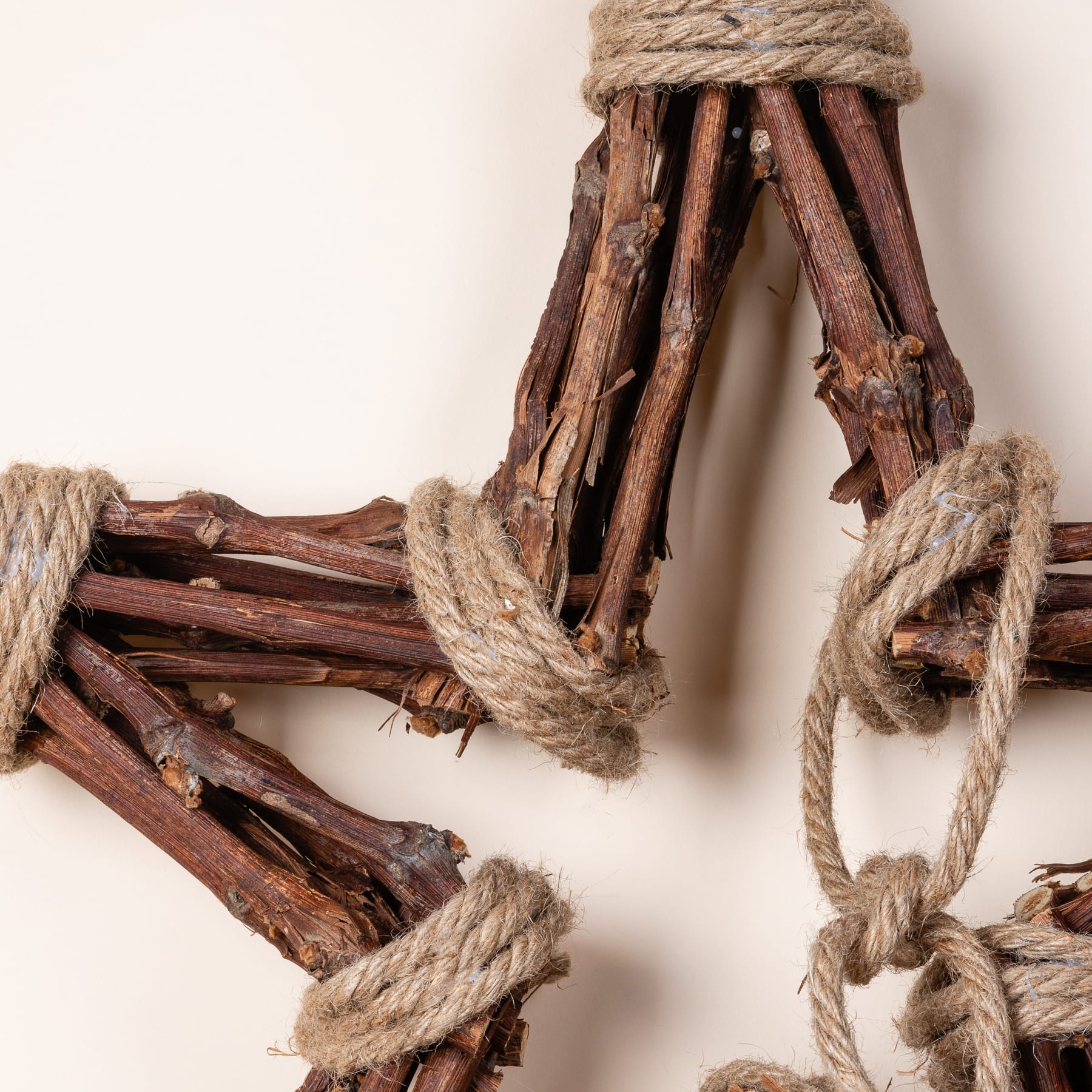 Rustikale Holzstäbe, mit einem groben Seil zusammengebunden, vor einem schlichten Hintergrund.