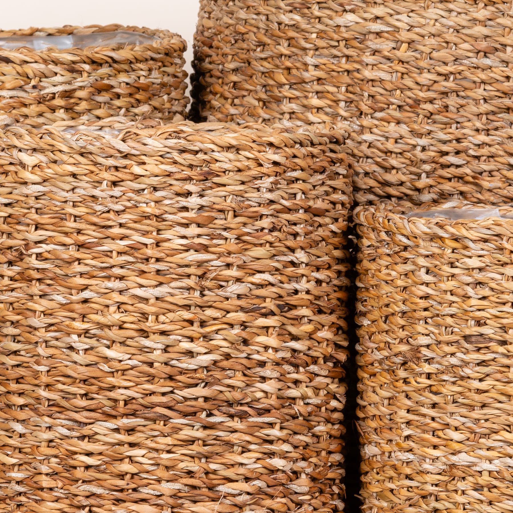 Das Bild zeigt eine Nahaufnahme mehrerer geflochtener Körbe oder Behälter aus natürlichen Materialien, wahrscheinlich Schilf oder Stroh, mit einem strukturierten und komplizierten Muster.