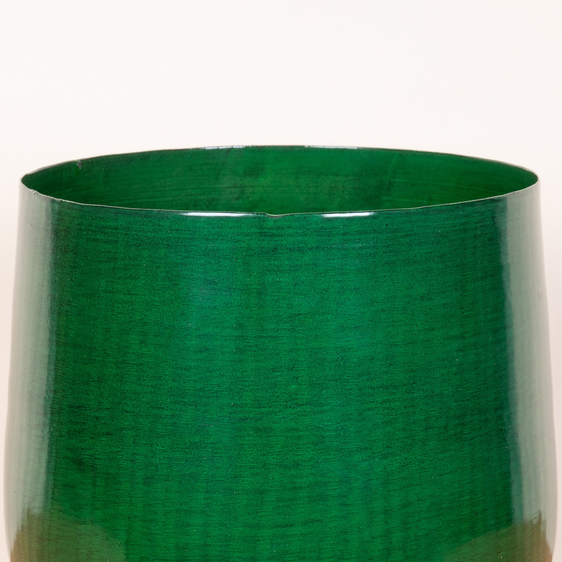 Ein leuchtend smaragdgrüner zylindrischer Behälter füllt den Rahmen, seine glänzende Oberfläche reflektiert das Licht.