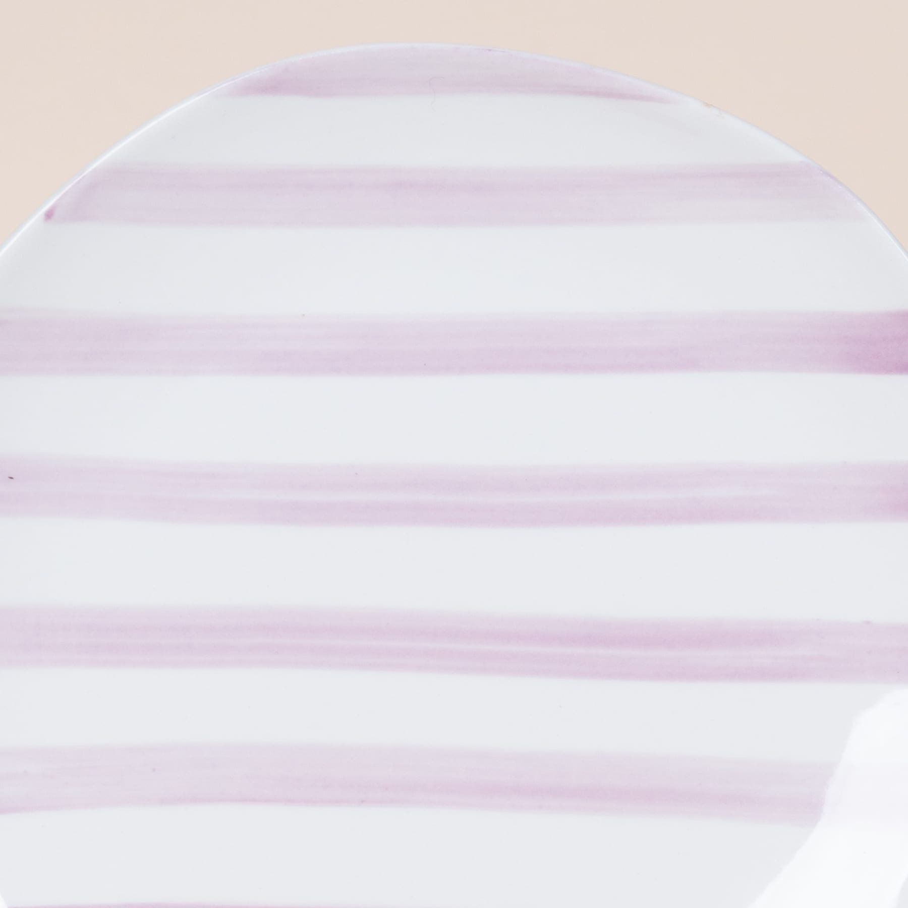 Das Bild zeigt ein kreisförmiges Muster aus abwechselnd weißen und hellvioletten horizontalen Streifen vor einem blassen Hintergrund.