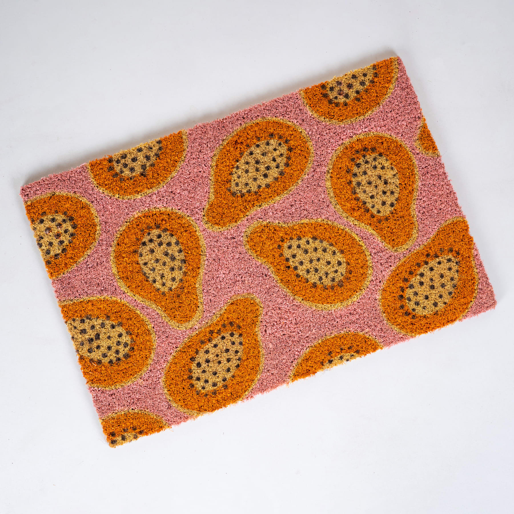 Das Bild zeigt einen lebendigen, gemusterten Stoff mit großen, stilisierten Papaya- oder Drachenfruchtformen in Orange- und Rosatönen vor hellem Hintergrund.