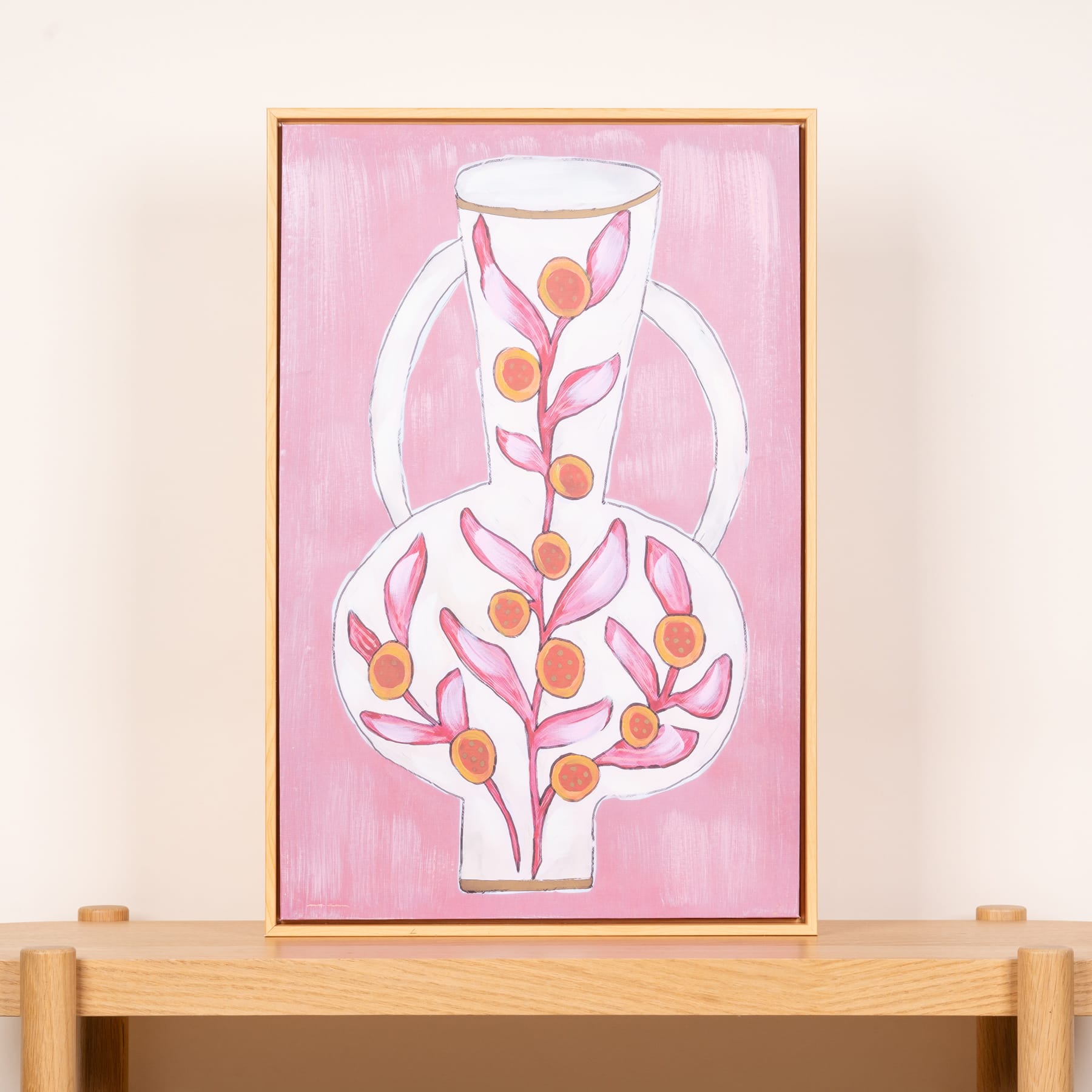 Ein gerahmtes Gemälde zeigt eine stilisierte vasenartige Form, gefüllt mit abstrakten orangefarbenen und rosafarbenen Blumenelementen vor einem zartrosa Hintergrund.