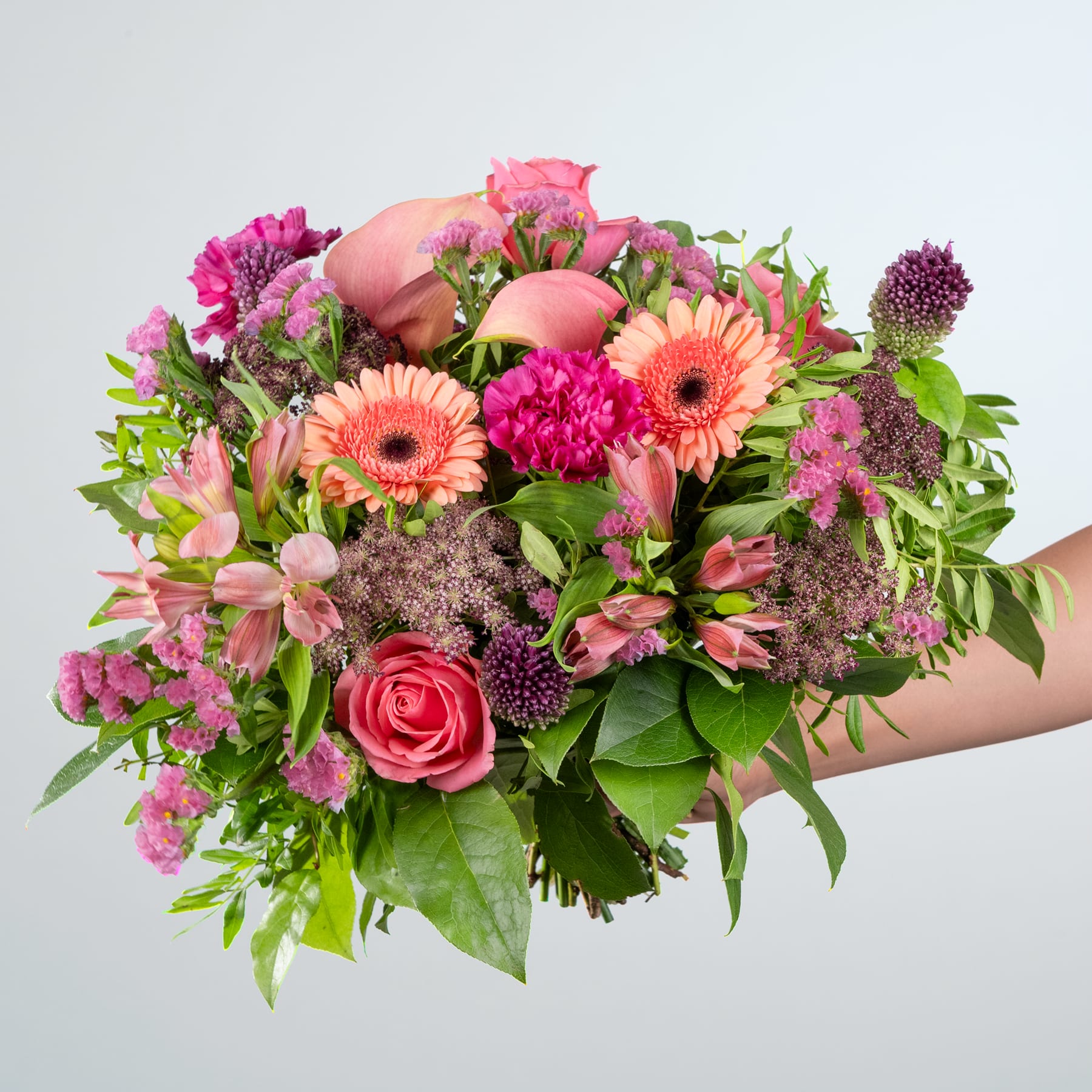 Ein leuchtender Strauß rosa und violetter Blumen, darunter Rosen, Gerbera und andere üppige Blüten, füllt den Rahmen vor einem schlichten weißen Hintergrund.