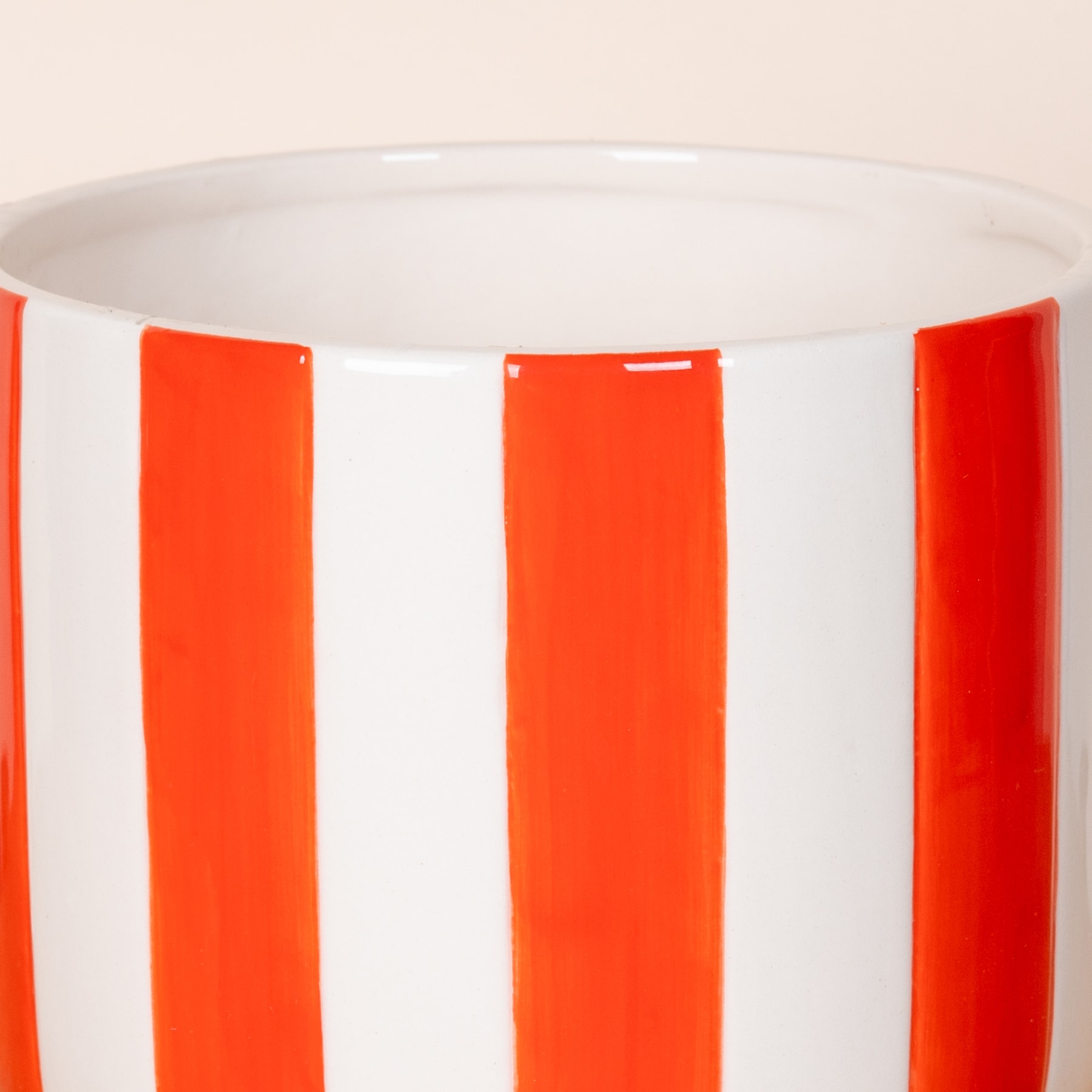Eine weiße Keramiktasse mit leuchtend orangefarbenen vertikalen Streifen auf der Außenseite.