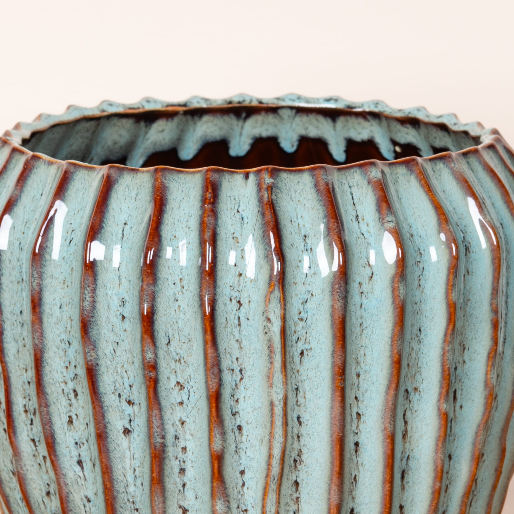 Eine Keramikvase mit strukturierter, geriffelter Oberfläche in Blau-, Grau- und Brauntönen, die ein auffälliges und optisch interessantes Muster erzeugt.