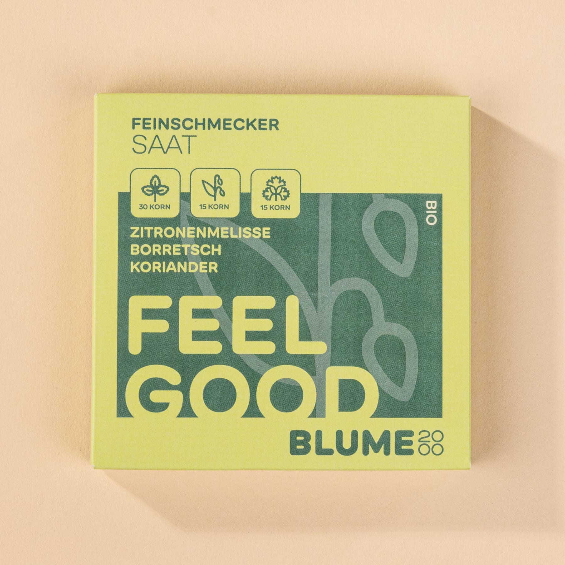 Eine grüne Box mit dem Text „FEEL GOOD BLUME“ und verschiedenen Symbolen, die Zutaten wie Zitronenmelisse, Borretsch und Koriander darstellen.