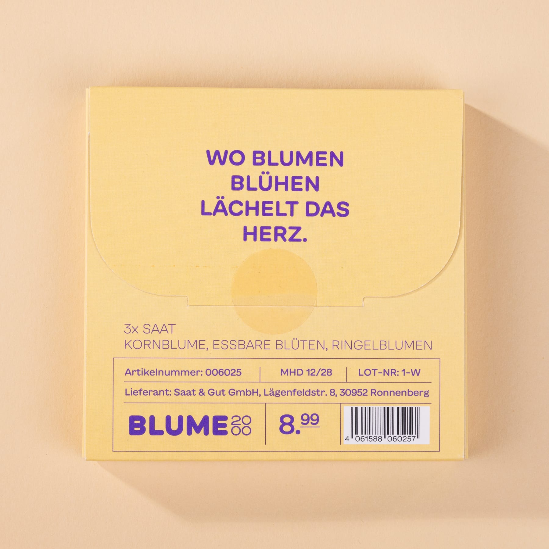 Das Bild zeigt eine gelbe Schachtel mit dem Text „WO BLUMEN BLÜHEN LÄCHELT DAS HERZ“. Die Schachtel enthält scheinbar ein Produkt namens „BLUME“ und zeigt zusätzliche Informationen wie den Preis und Herstellerangaben.