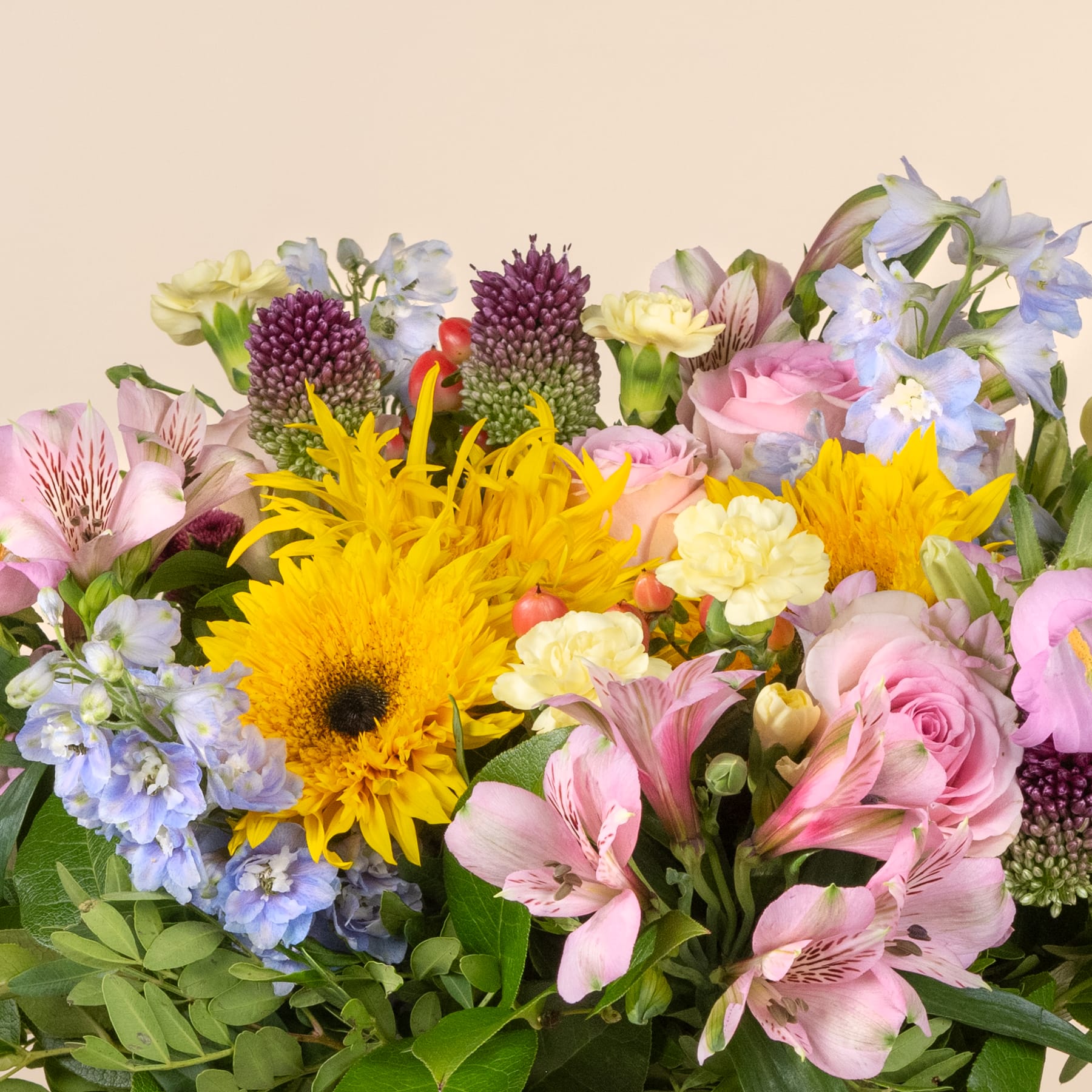 Ein lebendiger und farbenfroher Strauß verschiedener Blumen, darunter Sonnenblumen, Rosen und Inkalilien, vor einem weichen, neutralen Hintergrund.