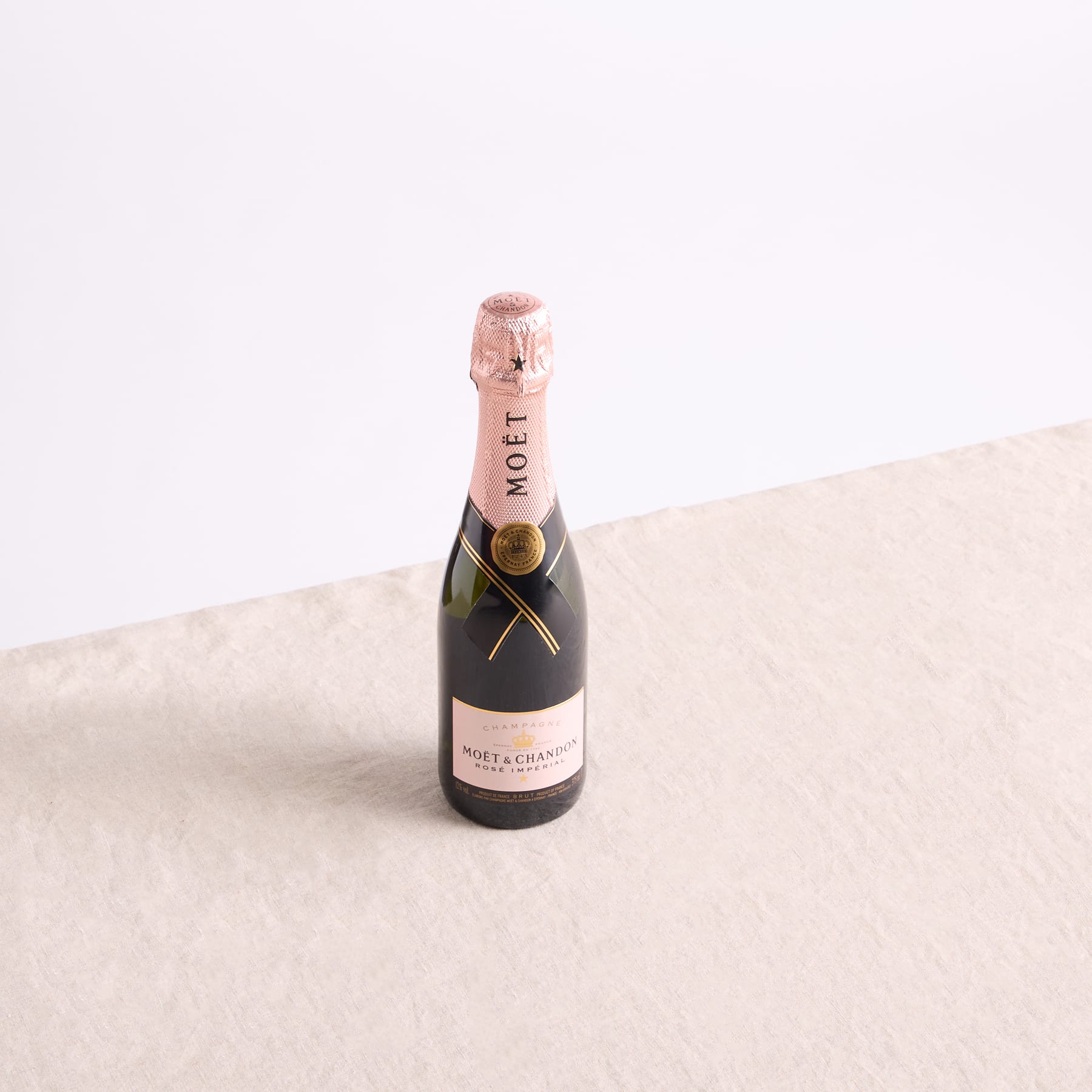 Eine Flasche Moet-Champagner steht auf einer hellen Fläche vor einem schlichten weißen Hintergrund.