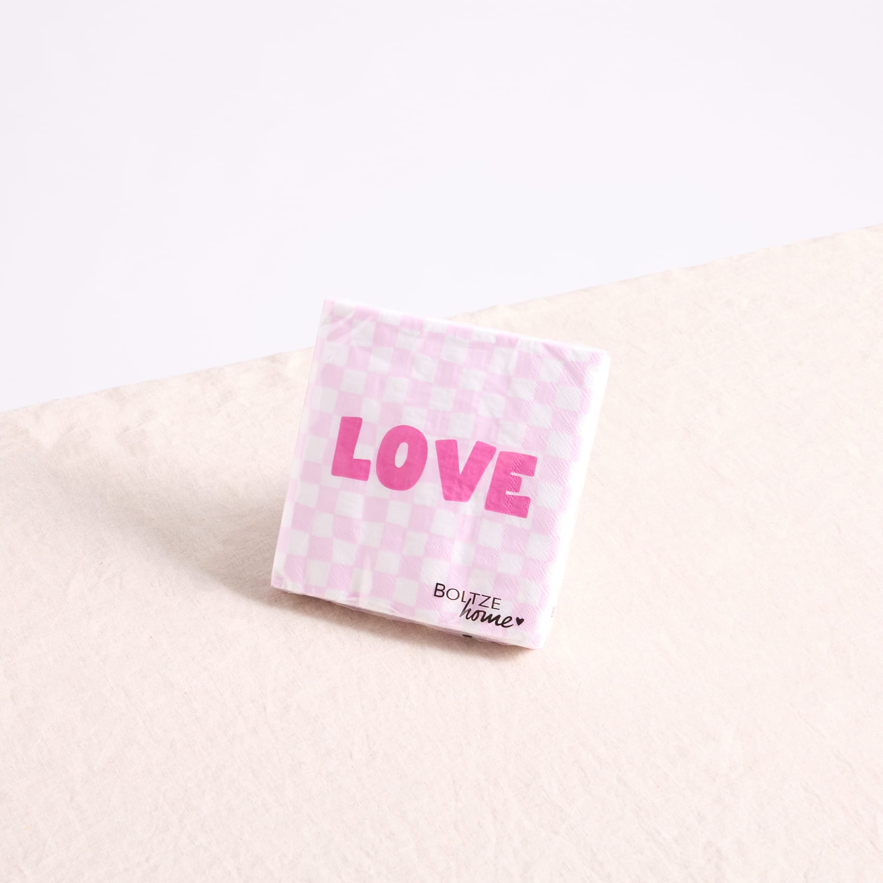 Auf einer hellen Oberfläche steht eine rosa-weiß gepunktete Schachtel mit dem Aufdruck „LOVE“.