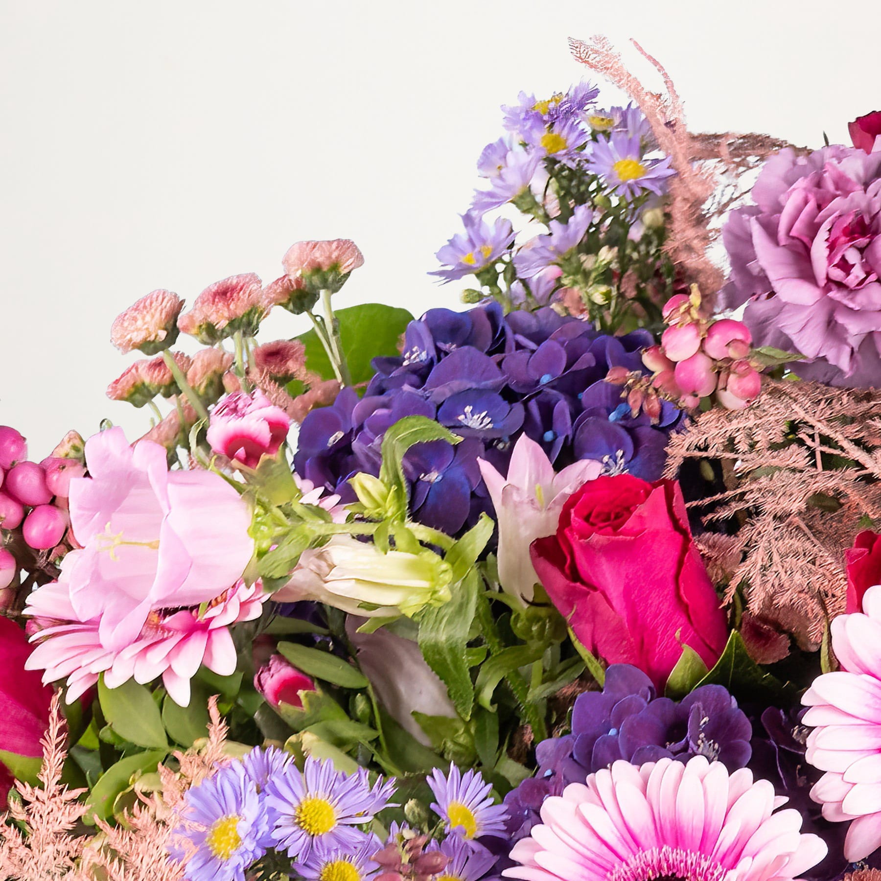 Ein lebendiger Strauß verschiedener bunter Blumen, darunter Rosen, Gänseblümchen und Veilchen, arrangiert vor einem schlichten Hintergrund.