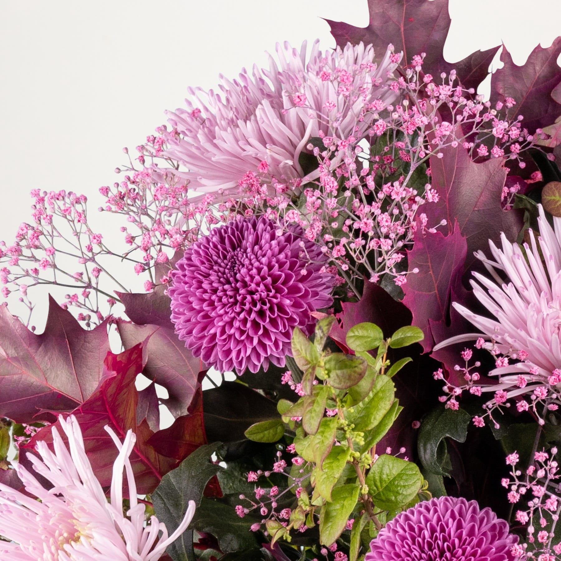 Ein lebendiger Strauß üppiger, rosa Chrysanthemen und anderer zarter Blumen vor neutralem Hintergrund.