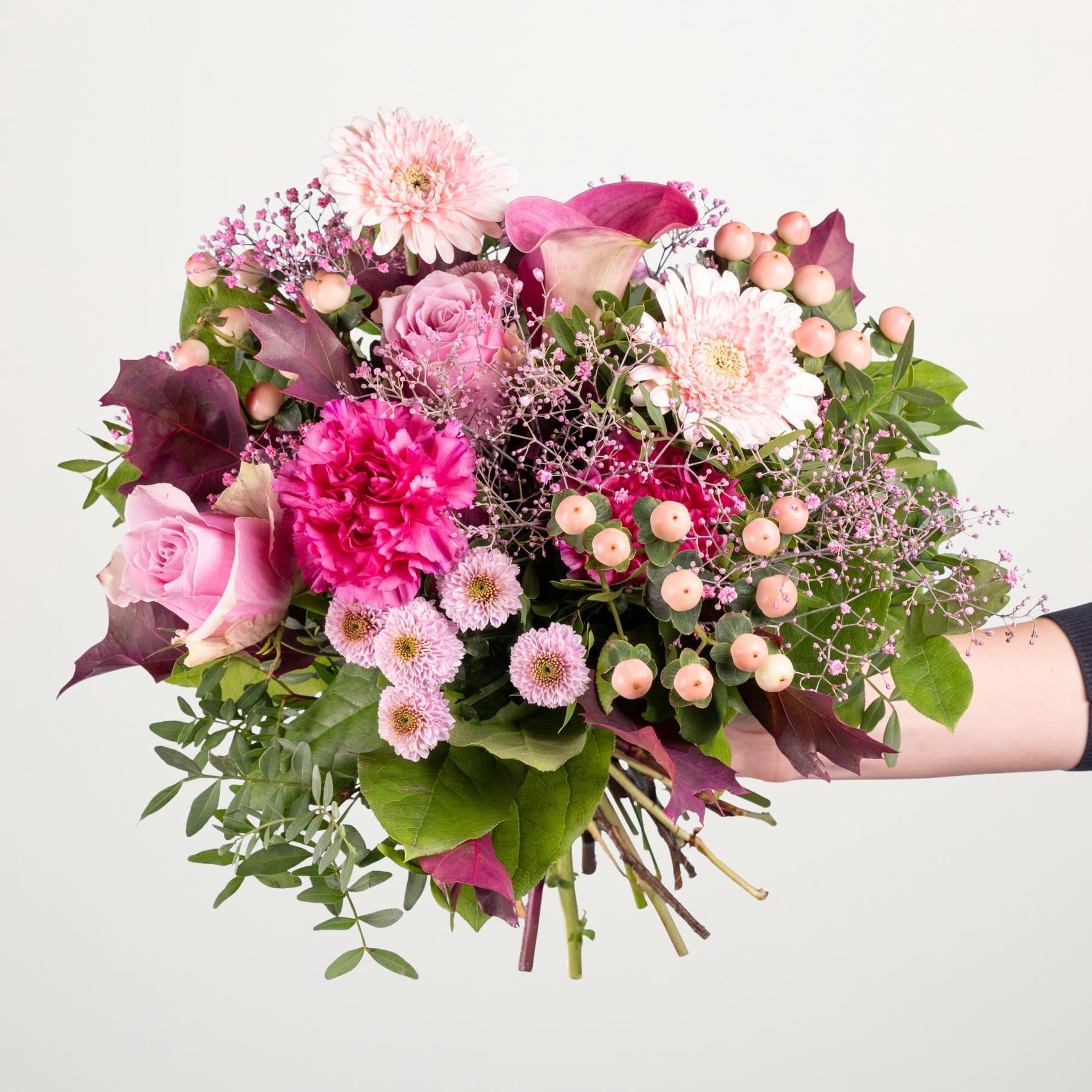 Ein lebendiger Strauß verschiedener rosa und violetter Blumen, darunter Rosen, Dahlien und Chrysanthemen, üppig und farbenfroh arrangiert vor einem schlichten weißen Hintergrund.