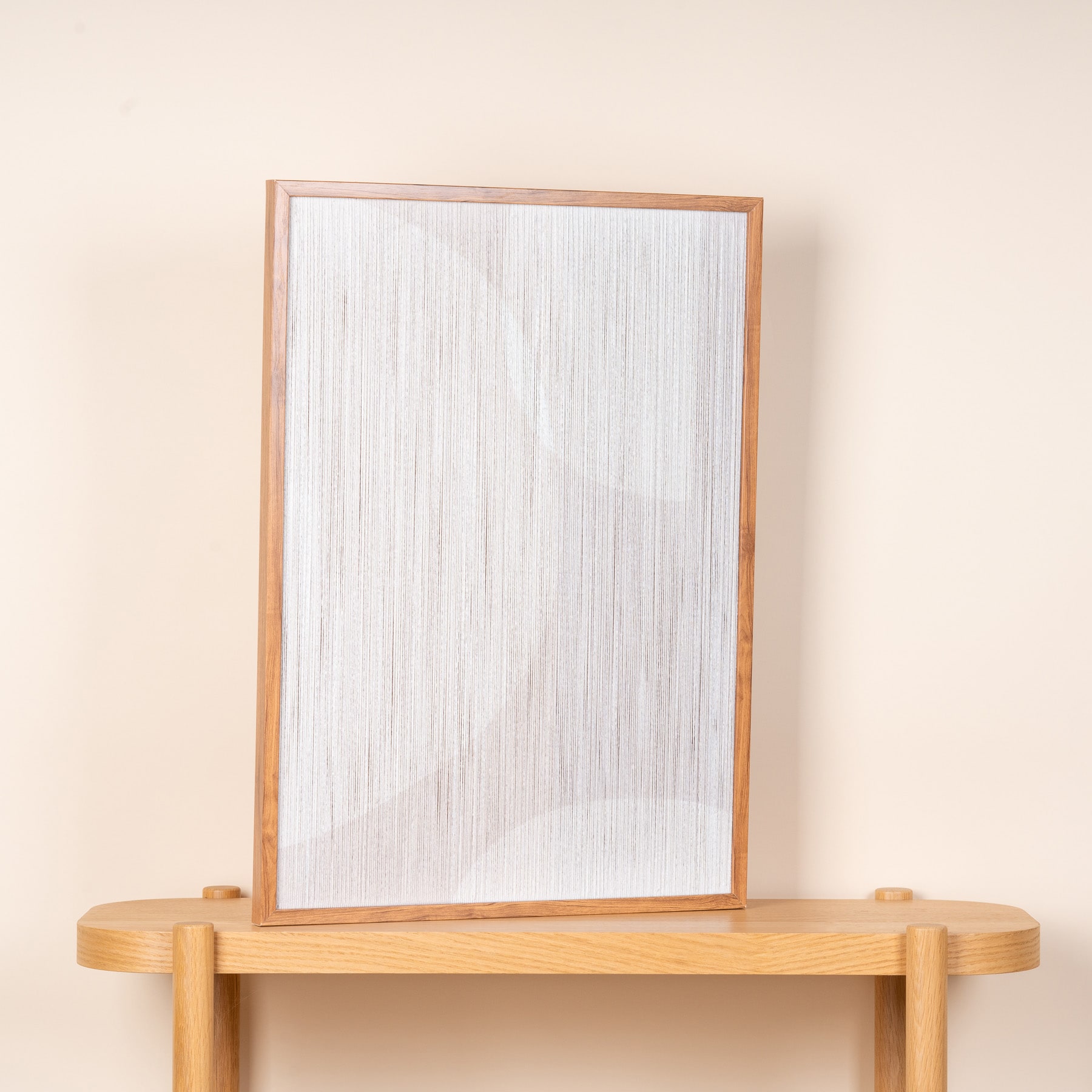 Ein Spiegel mit Holzrahmen steht auf einem Holzregal vor einer hellen Wand.