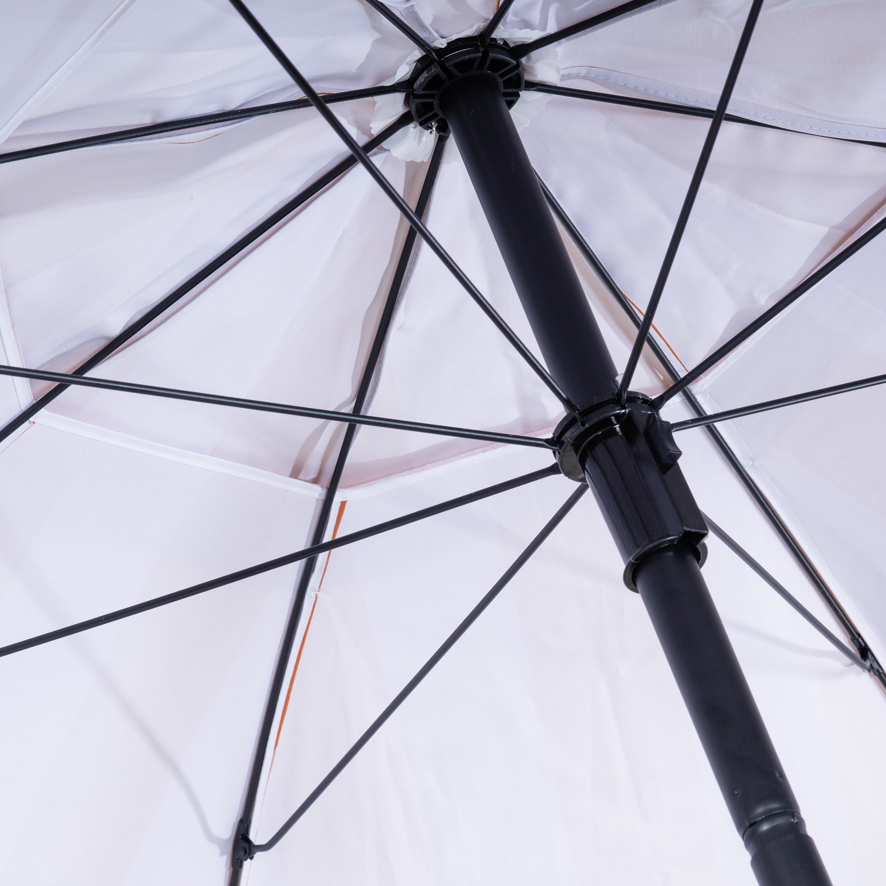 Ein schwarzer Regenschirm mit transparentem Schirmdach, dessen komplizierter Rahmen aus Rippen und Speichen vor einem hellen, unscharfen Hintergrund sichtbar ist.