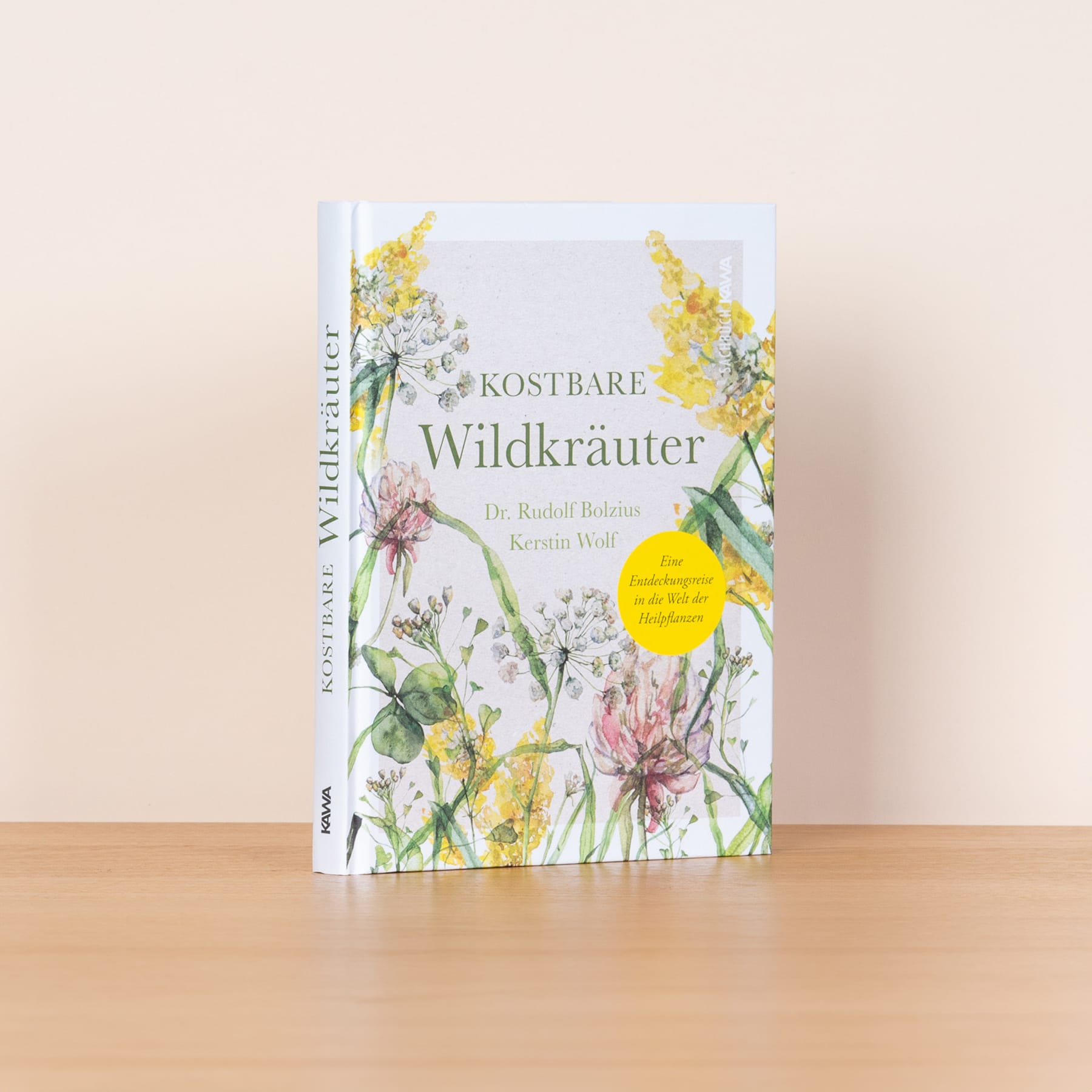Ein Buch mit dem Titel „Kostbare Wildkräuter“ von Rudolf Bölling mit einer farbenfrohen Illustration verschiedener Wildblumen und Kräuter auf einer Holzoberfläche.