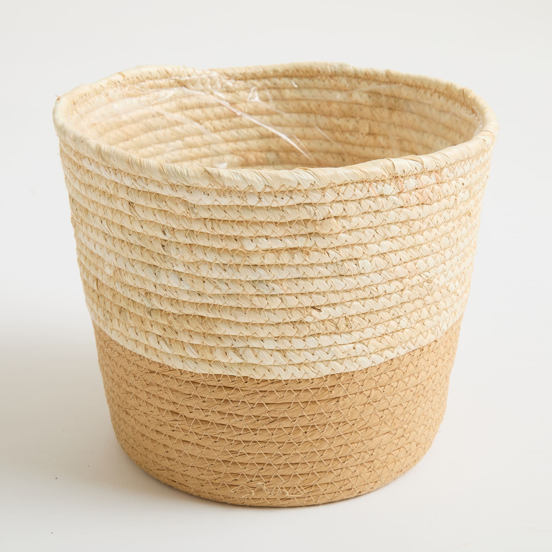 Ein geflochtener Korb in Beige und Hellbraun auf einem schlichten weißen Hintergrund.