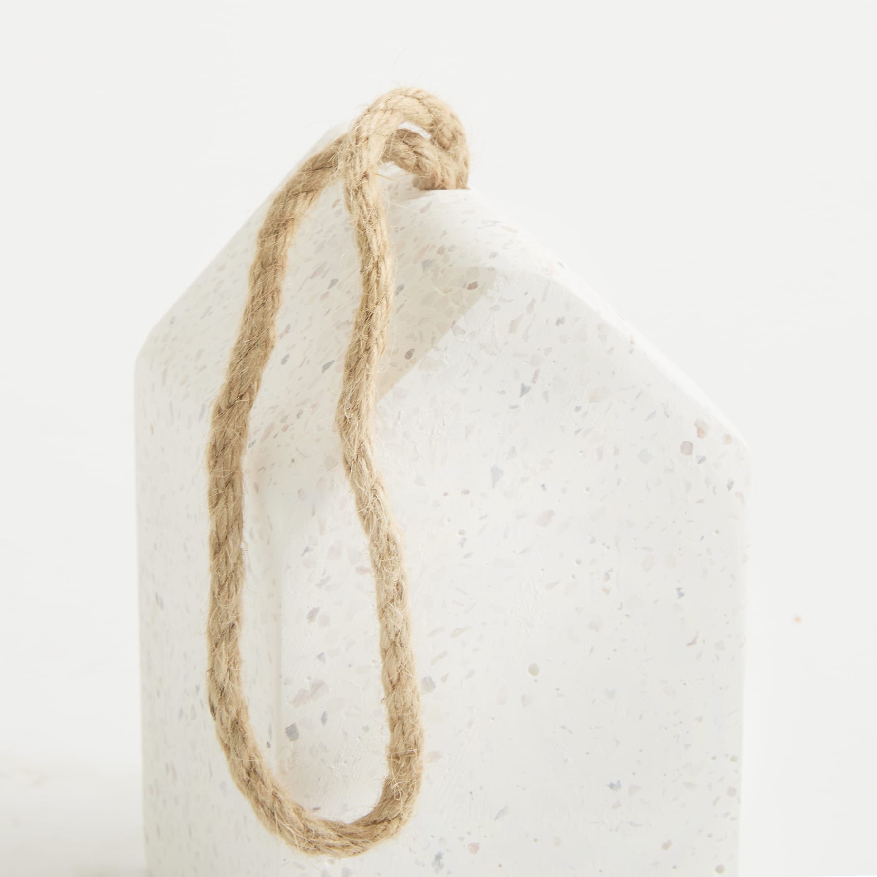 Eine weiße, strukturierte Oberfläche mit einem aufgerollten Seil oder einer Schnur im Vordergrund.