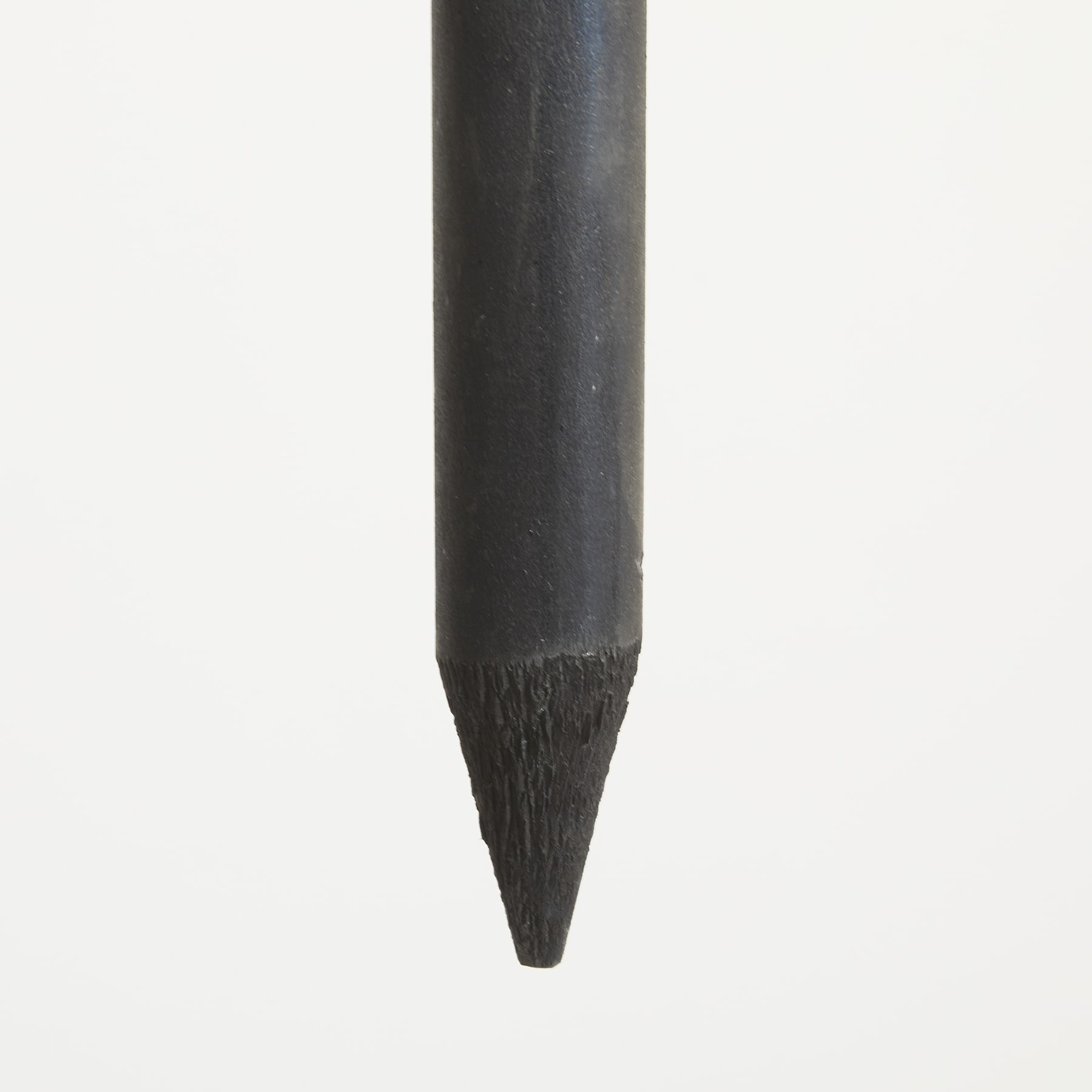 Ein schwarzer Bleistift mit einer spitzen Spitze steht vor einem schlichten weißen Hintergrund.